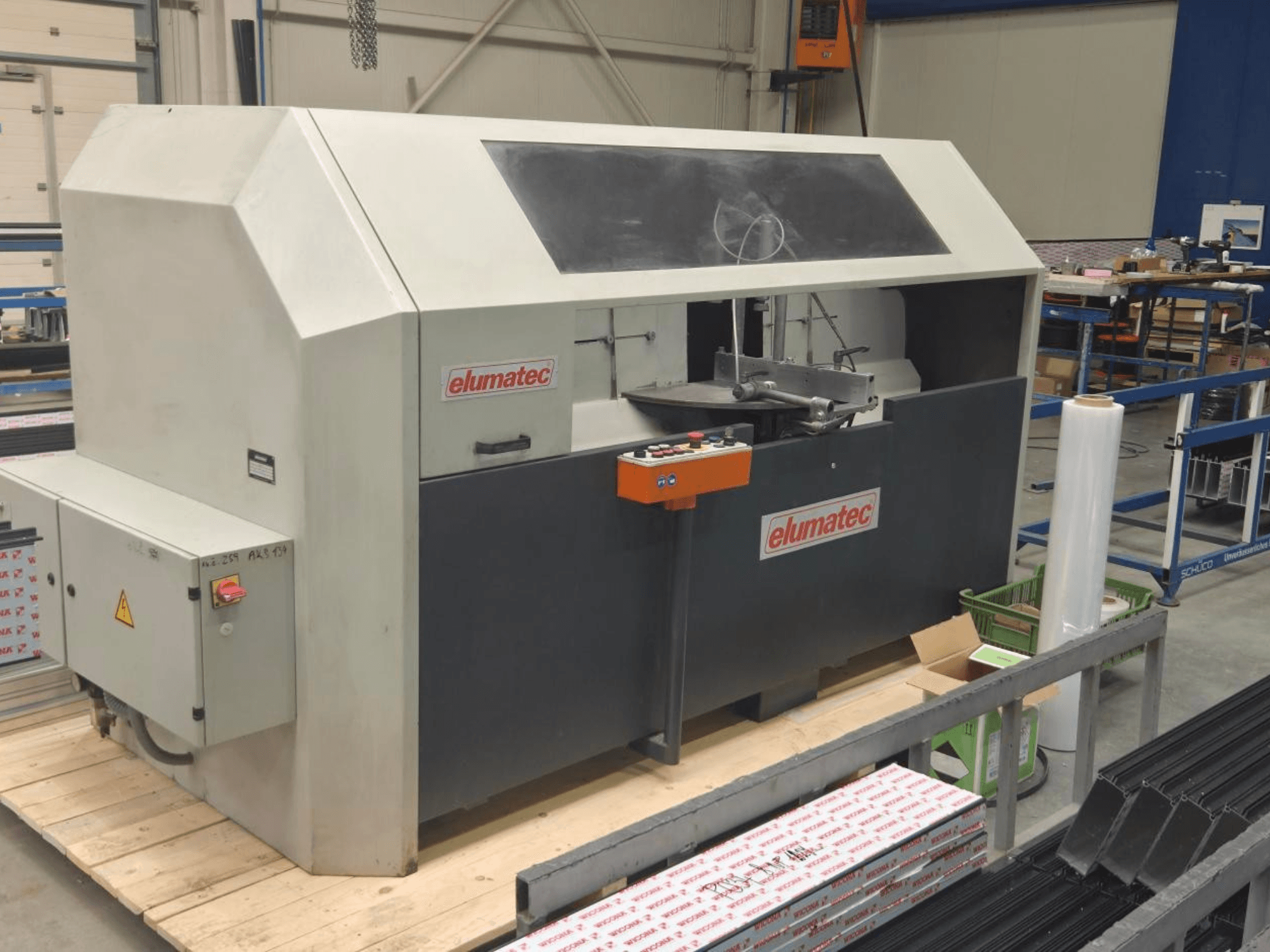 Diskinis metalo pjūklas "Elumatec AKS 134", vaizdas iš priekio, valdymo skydelis ir pjovimo zona ant medinės platformos.