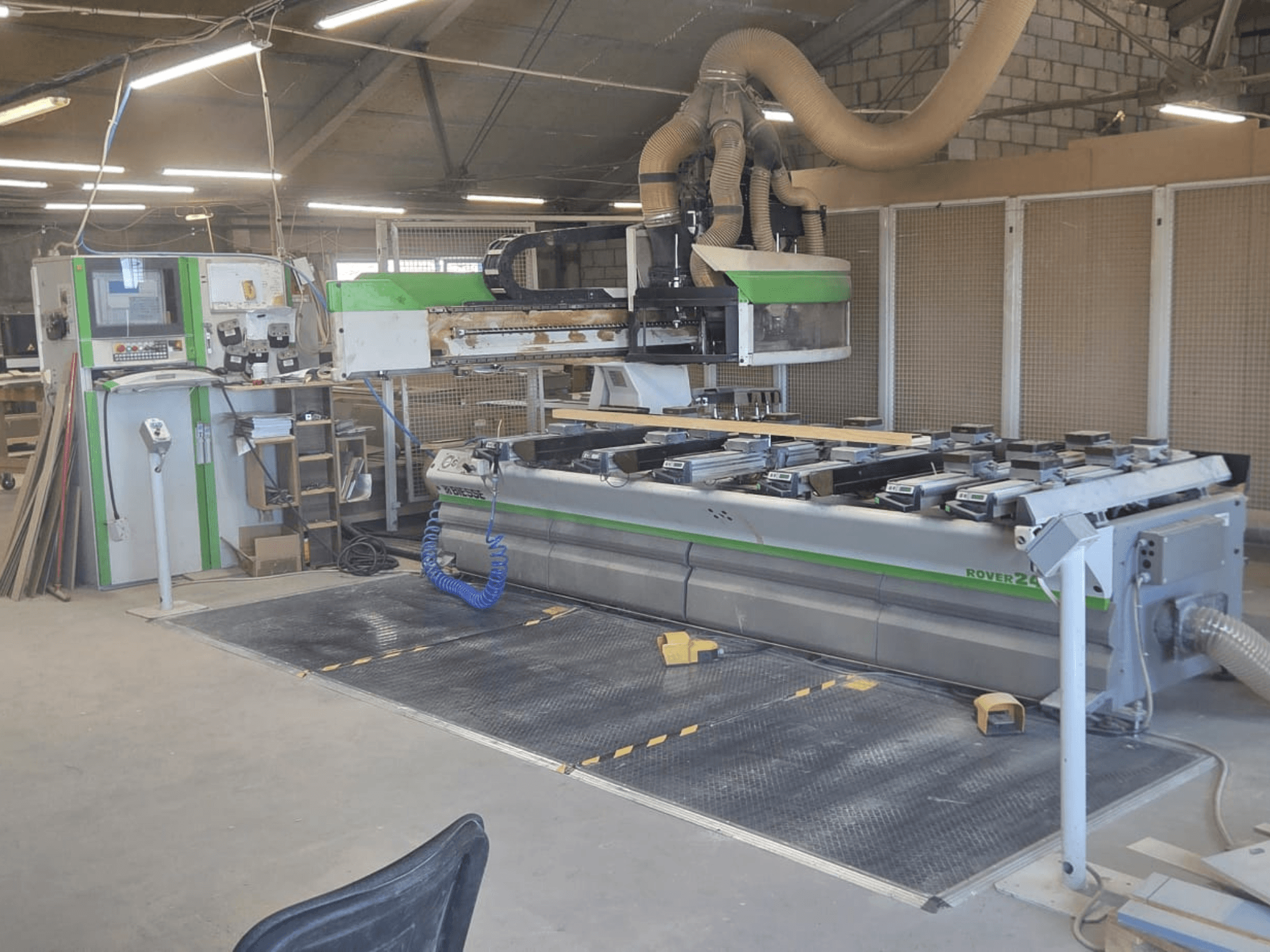 CNC apdirbimo centras "BIESSE Rover 24S" dirbtuvėse su valdymo pultu ir dideliu darbo paviršiumi su medinėmis detalėmis.