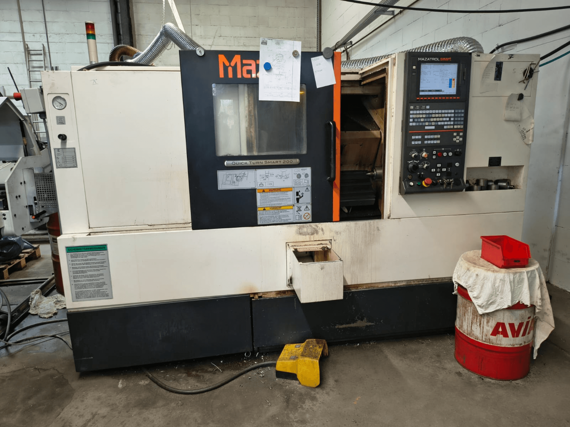 „Mazak Quick Turn Smart 200“ – horizontalus tekinimo staklės, vaizdas iš priekio, kuriame matomas valdymo pultas, aušinimo skysčio bakas ir žymės.