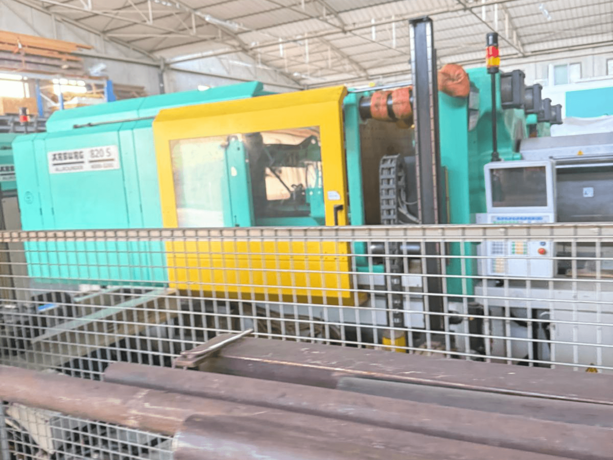 Hidraulinės liejimo mašinos "Arburg SELECTA 820 S 4000-3200", šoninis vaizdas, matomas valdymo skydelis ir ryškus geltonos ir arbatžolių spalvos dizainas.