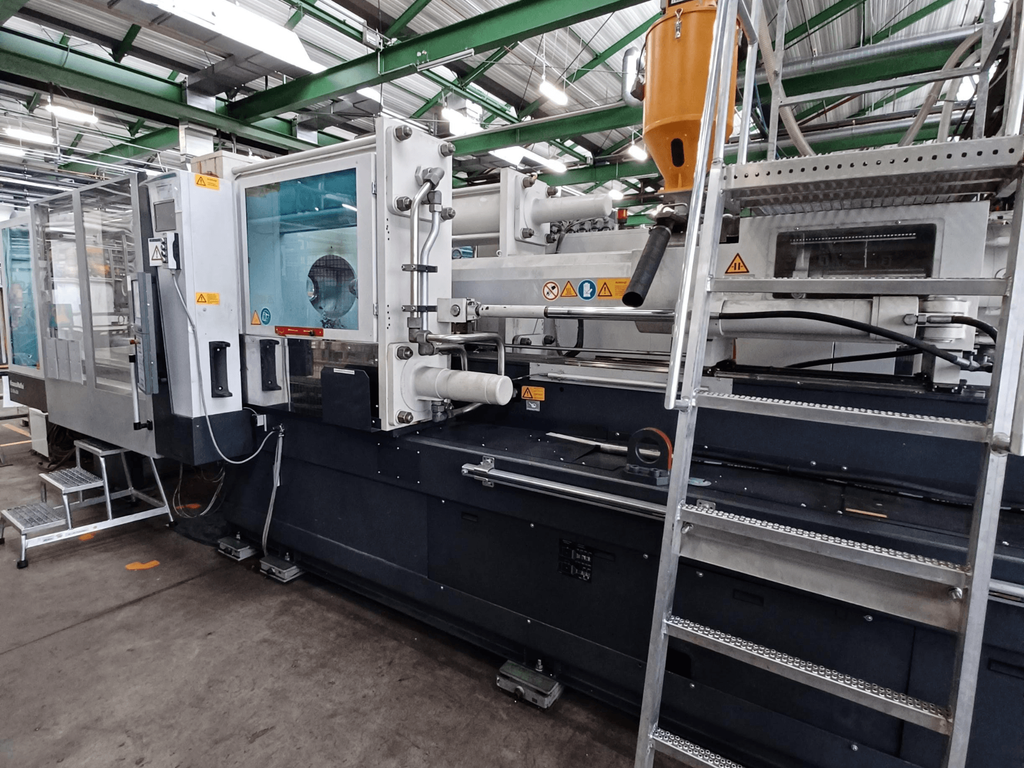 Pramoninė liejimo mašina su aiškiu priekiniu vaizdu, kuriame matyti prekės ženklo žymės, valdymo skydelis ir medžiagų bunkeris.