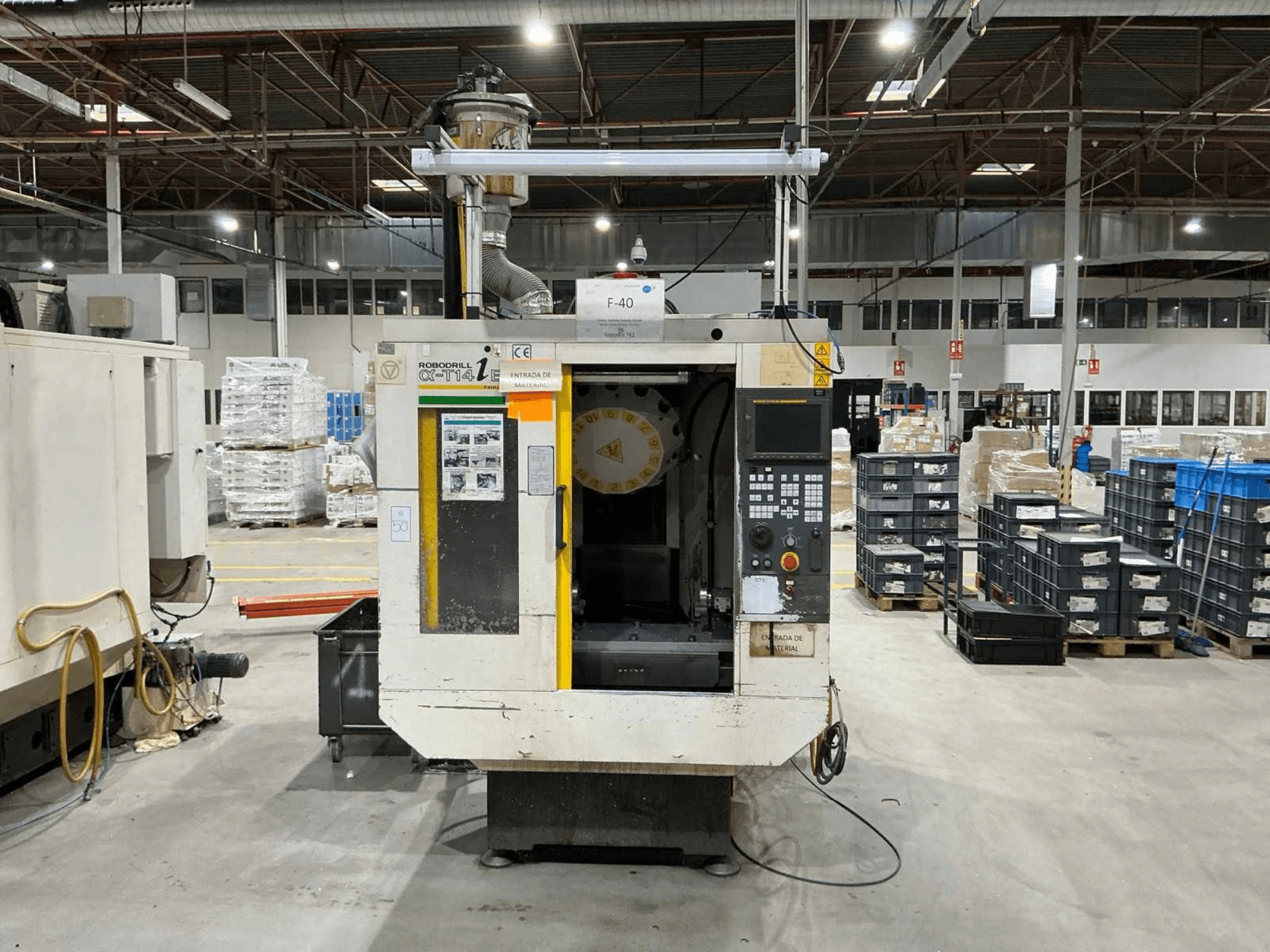 FANUC ROBODRILL α-T14iB vertikalus apdirbimo centras gamykloje, priekinis vaizdas, rodantis valdymo skydelį ir įrankių laikiklį.