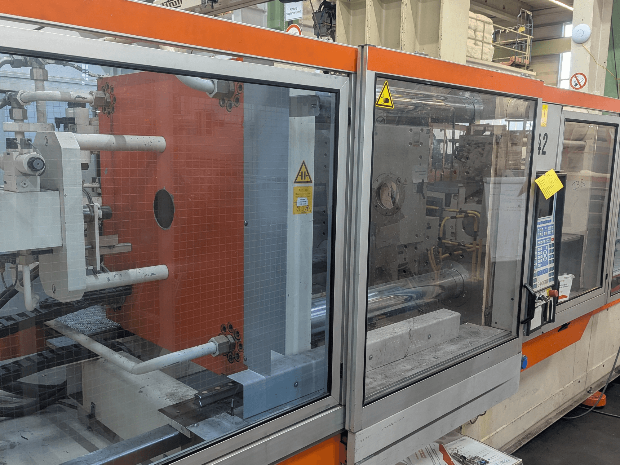 Hidraulinės įpurškimo mašinos DEMAG SYSTEC 80/420-310 vaizdas iš priekio su matomu valdymo skydeliu ir mašinų komponentais.