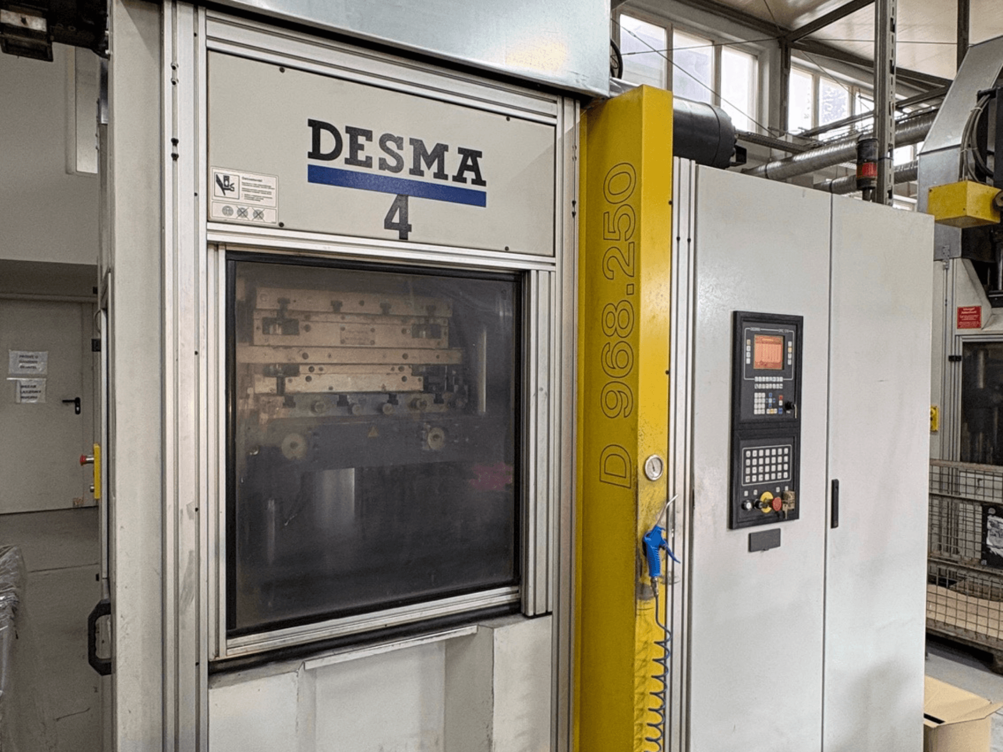 Vertikaliojo įpurškimo liejimo mašina "Kloeckner Desma 968.250", priekinis vaizdas, kuriame matyti valdymo skydelis ir mašinos detalės.