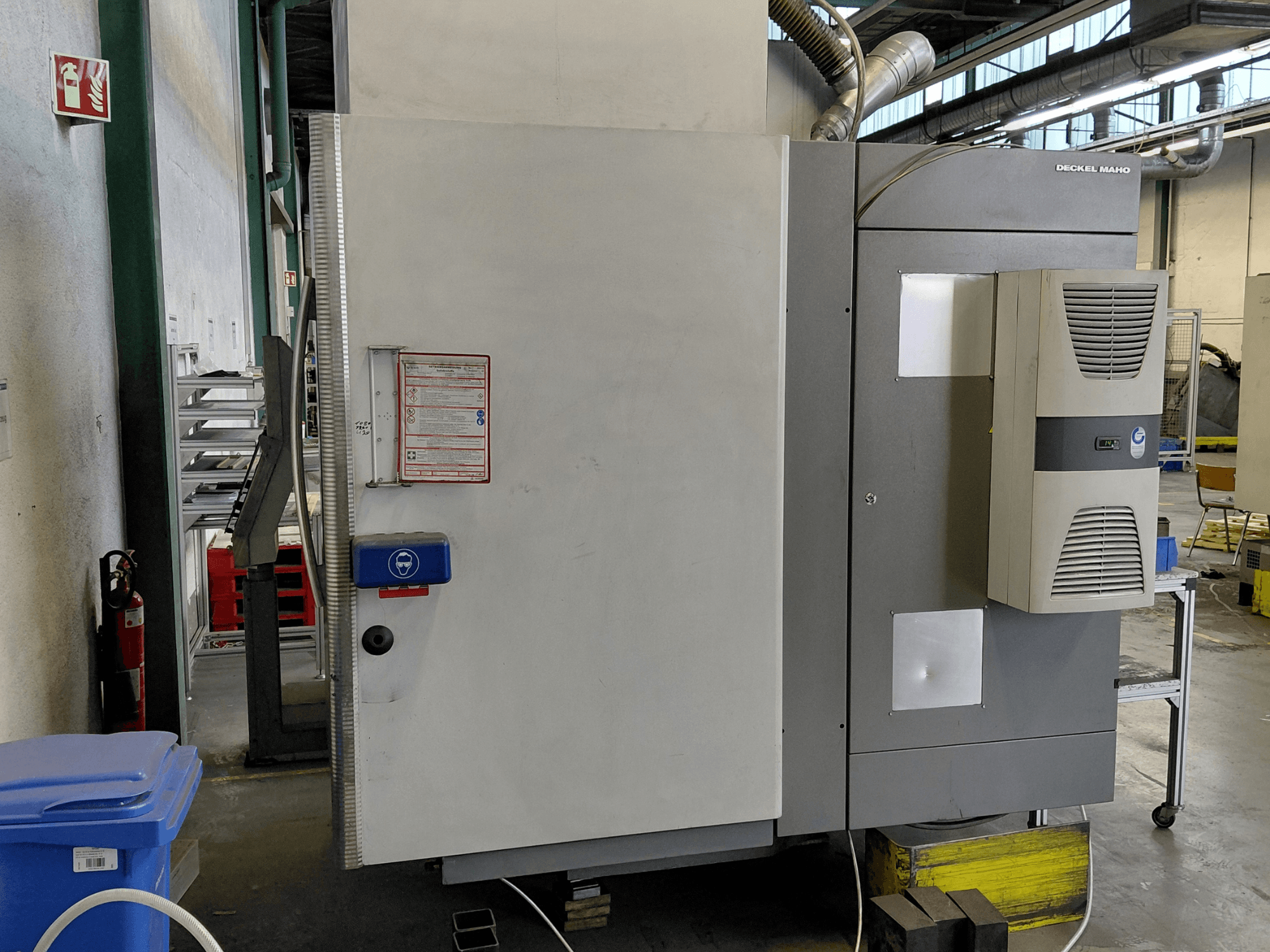 Vertikalaus apdirbimo centro DECKEL MAHO DMC 635 V vaizdas iš šono, matomas valdymo skydelis ir saugos etiketės.