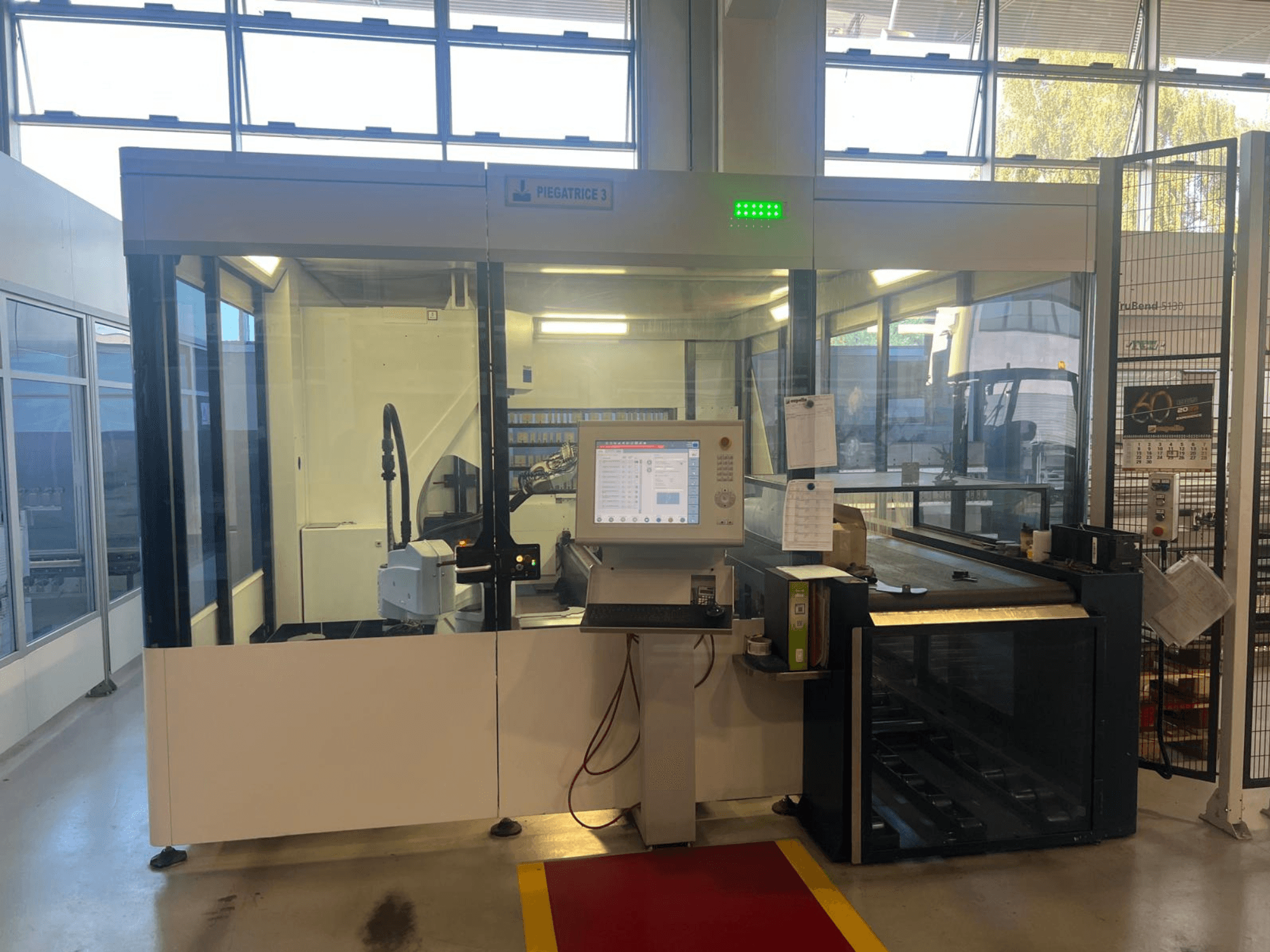 Pramoninės lenkimo staklės, modelis Piegatrice 3, vaizdas iš priekio su valdymo pultu ir roboto ranka, gerai apšviestose dirbtuvėse.