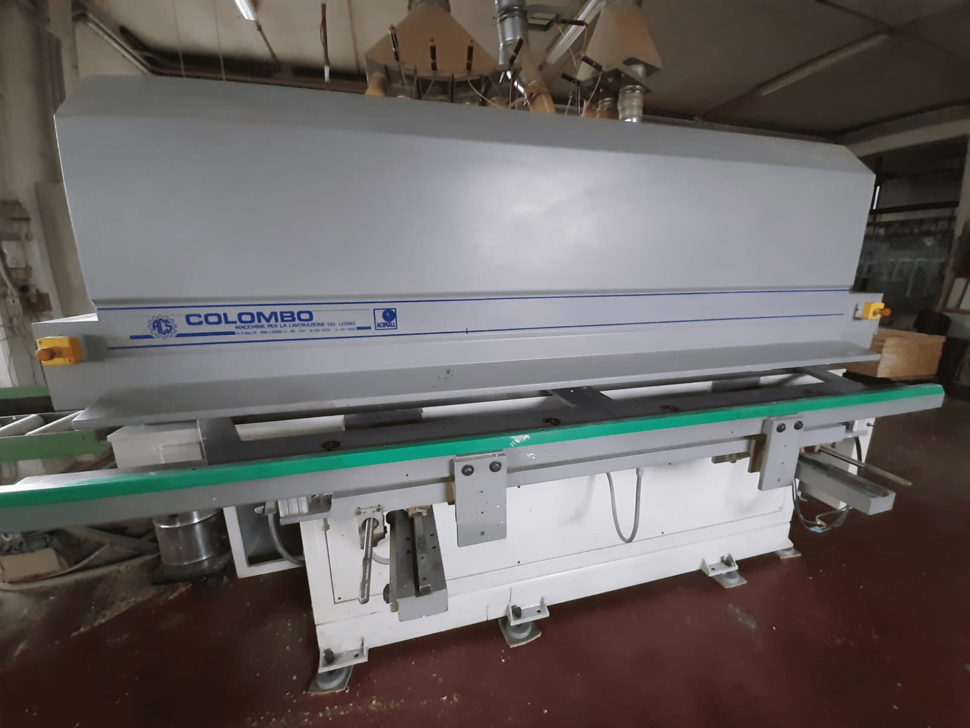 "Colombo" medienos apdirbimo staklės, vaizdas iš priekio: ilgas žalias stalas, valdymo mygtukai ir pilkas korpusas su mėlynais akcentais.