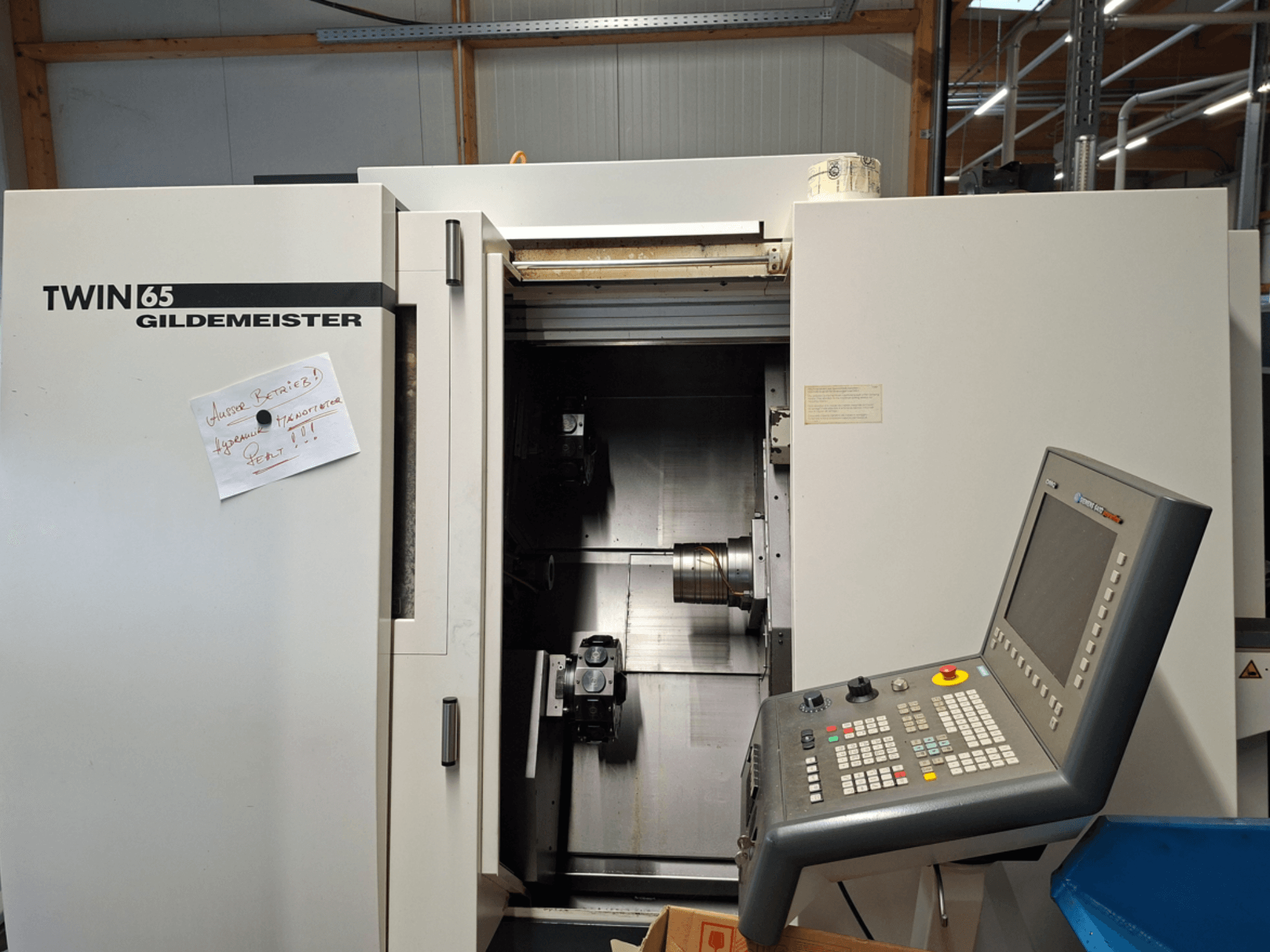 Gildemeister TWIN 65 CNC tekinimo staklės, priekinis vaizdas, kuriame matomas valdymo skydelis ir iš dalies atvira kamera su matomais mechanizmais.