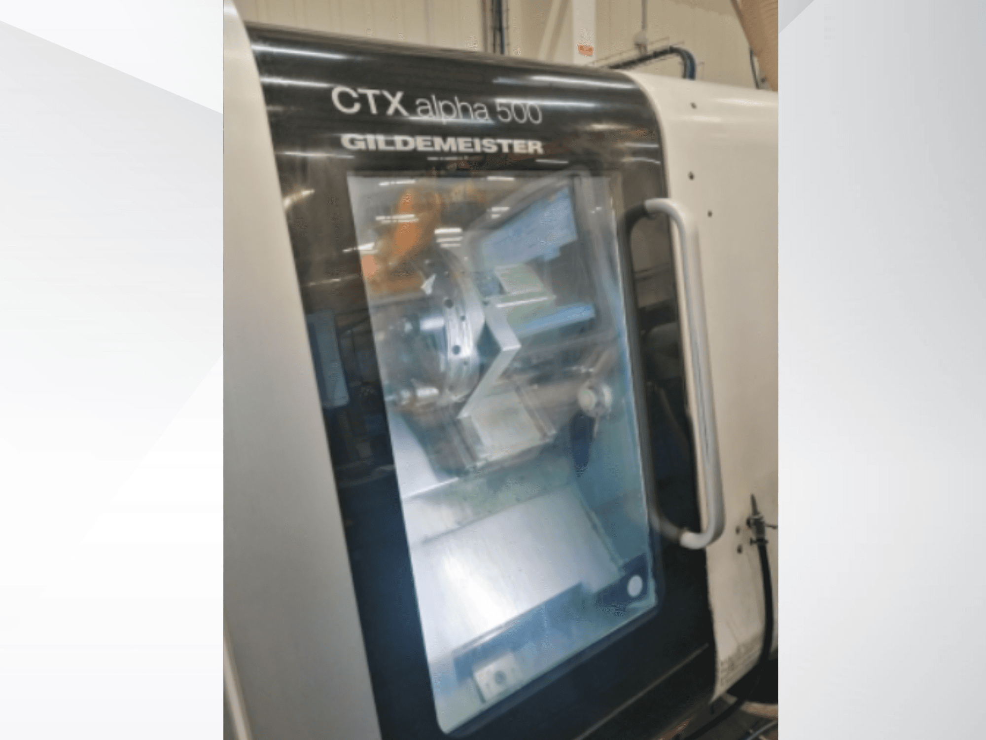 CTX alpha 500 "Gildemeister" CNC staklės, vaizdas iš priekio, pro stiklines dureles matomas suklys ir apdirbimo zona.