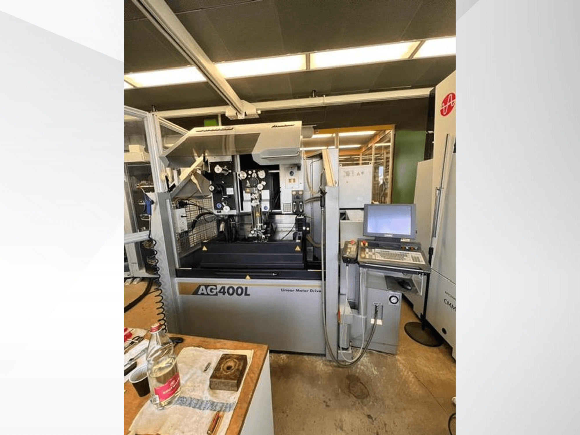 AG400L linijinės variklio pavaros mašina, vaizdas iš priekio, matomas valdymo skydelis ir darbo zona su saugos funkcijomis.