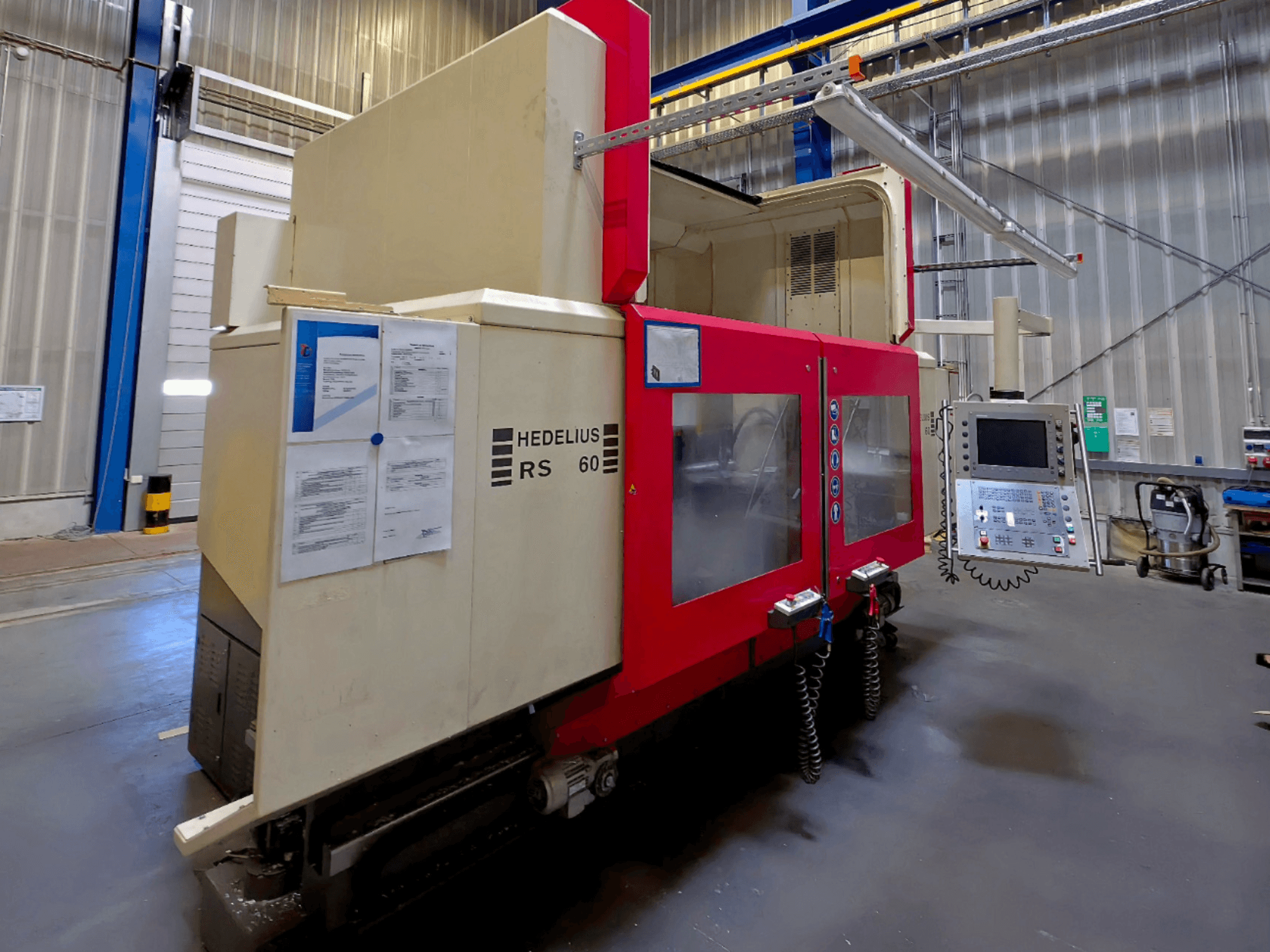 HEDELIUS RS 60 K - 2000 vertikalusis apdirbimo centras, vaizdas iš šono, matomas valdymo skydelis ir saugos instrukcijos.