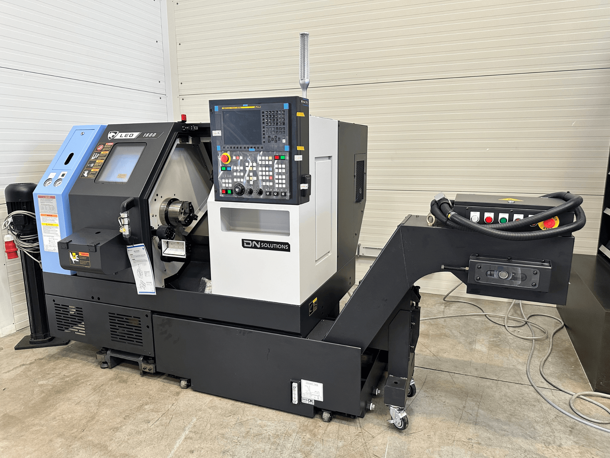 DN SOLUTIONS "Leo 1600" tekinimo frezavimo centro su skaitmeniniu valdymo pultu ir įrankių laikikliu ant juodo pagrindo vaizdas iš priekio.