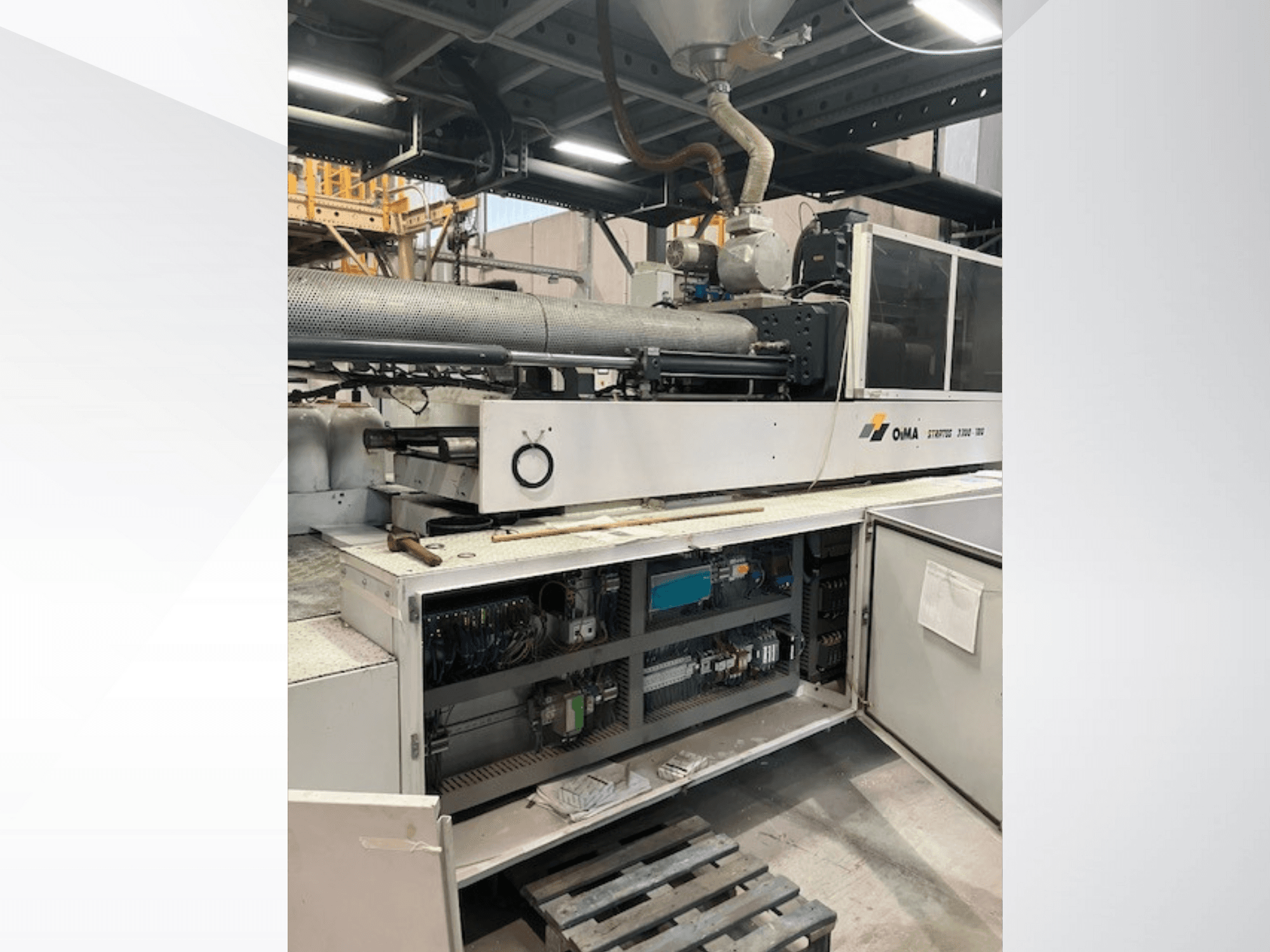 OMA ekstruderio 3500 priekinis vaizdas, kuriame matomos darbinės dalys, valdymo skydelis ir laidų detalės. Sunkiosios mašinos pramoninėje aplinkoje.