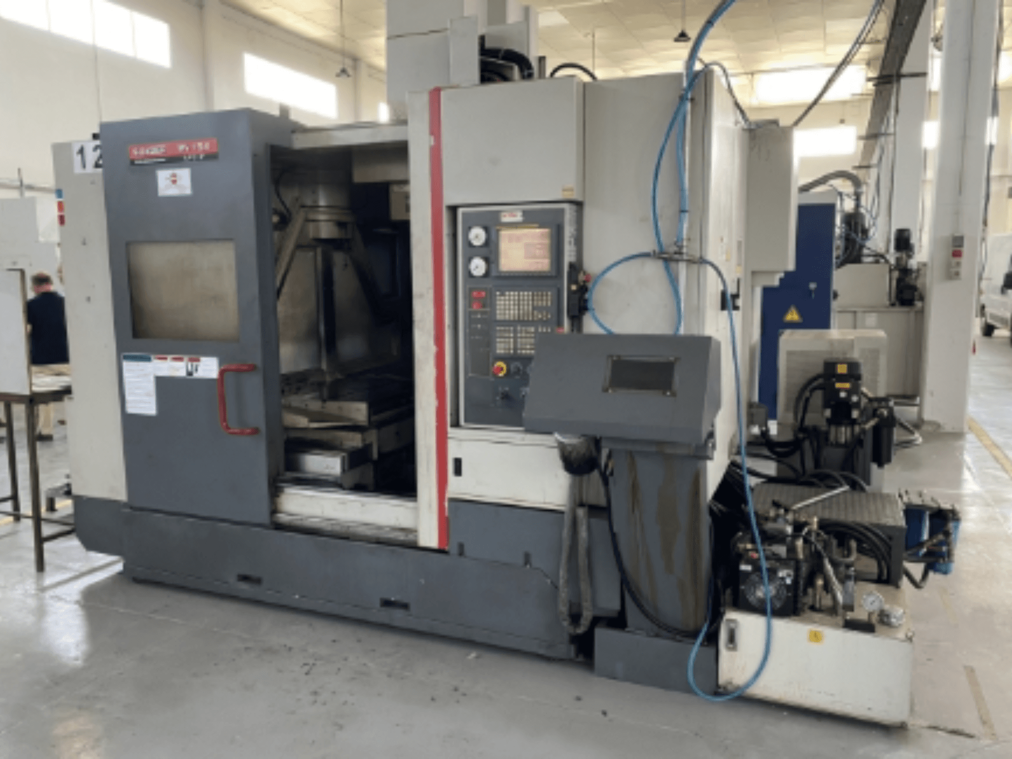 Vertikalaus apdirbimo centro "Quaser MV154APC-912" priekinis vaizdas, kuriame matyti valdymo skydelis, atidarytos durys ir staklių sudedamosios dalys.