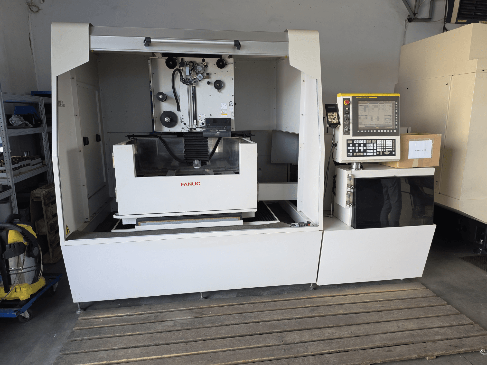 „FANUC ROBOCUT alpha-1iD“ vielos elektroerozijos staklės, vaizdas iš priekio, kuriame matomas valdymo skydas, darbo zona ir kompaktiška konstrukcija dirbtuvėse.