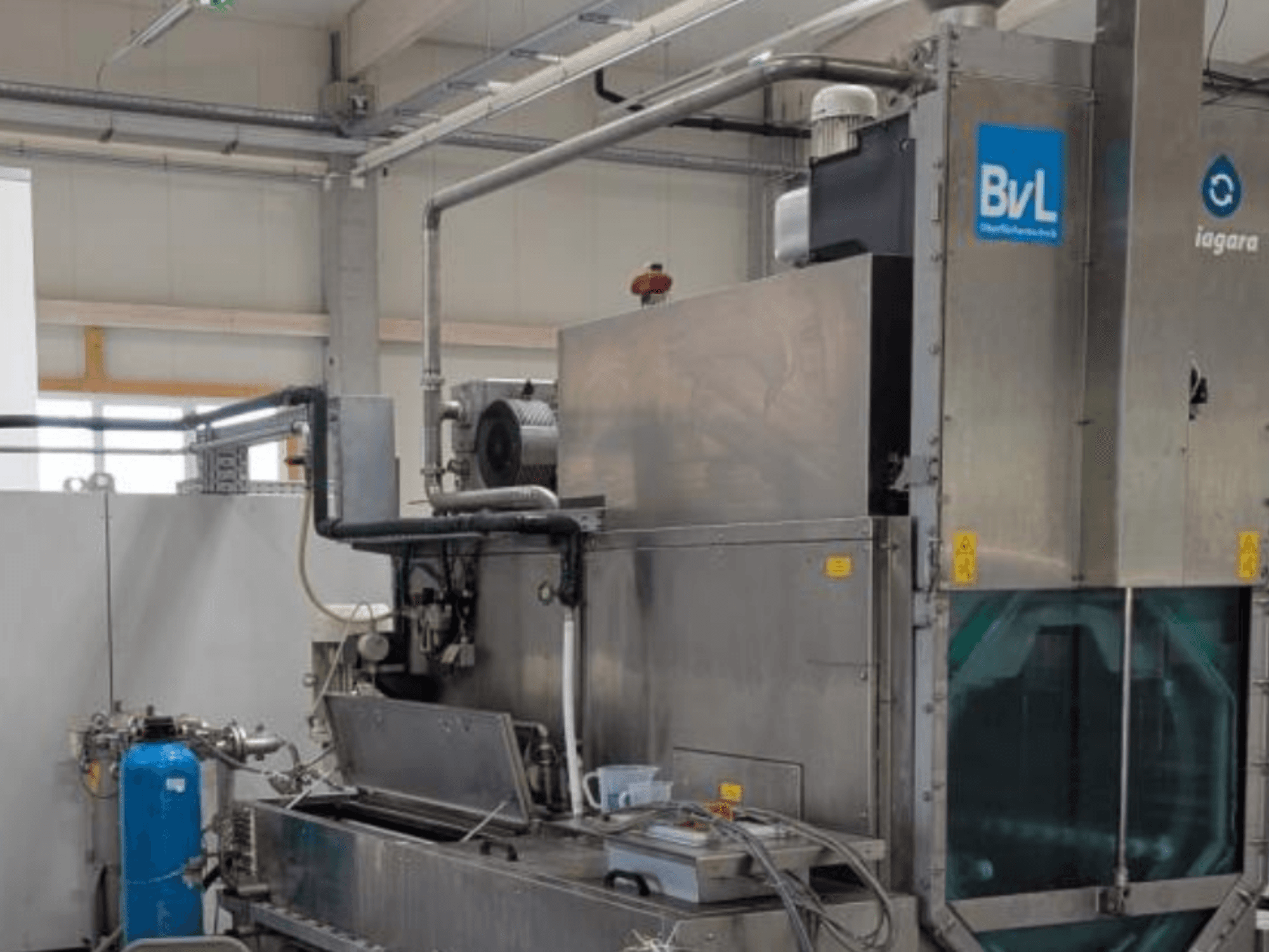 „BvL Niagara DFS 800-2T“ staklės gamykloje, šoninis vaizdas, kuriame matoma metalinė konstrukcija ir prijungtos žarnos.