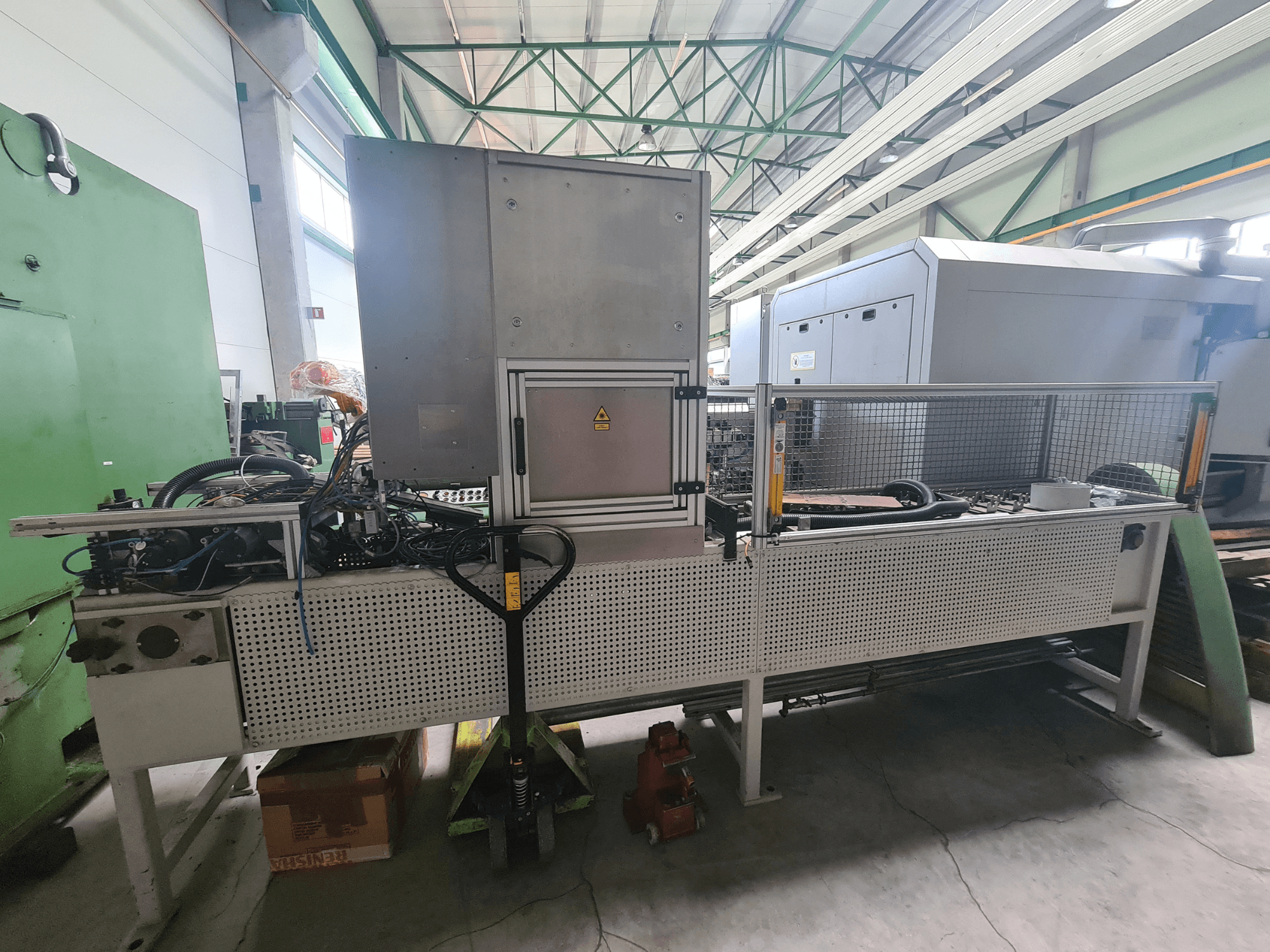 Pramoninės mašinos su metaliniu rėmu, žarnomis ir valdymo skydu, žiūrint iš šono gamykloje.