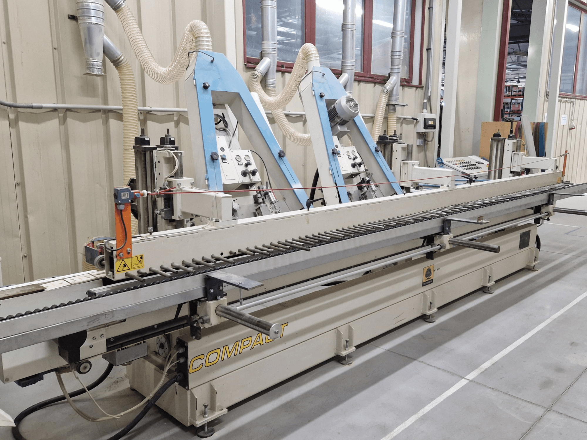 Juostinis šlifuoklis TECNOLEGNO COMPACT 52 dirbtuvėse, iš šono matomas valdymo skydelis ir šlifavimo juostos mechanizmas.