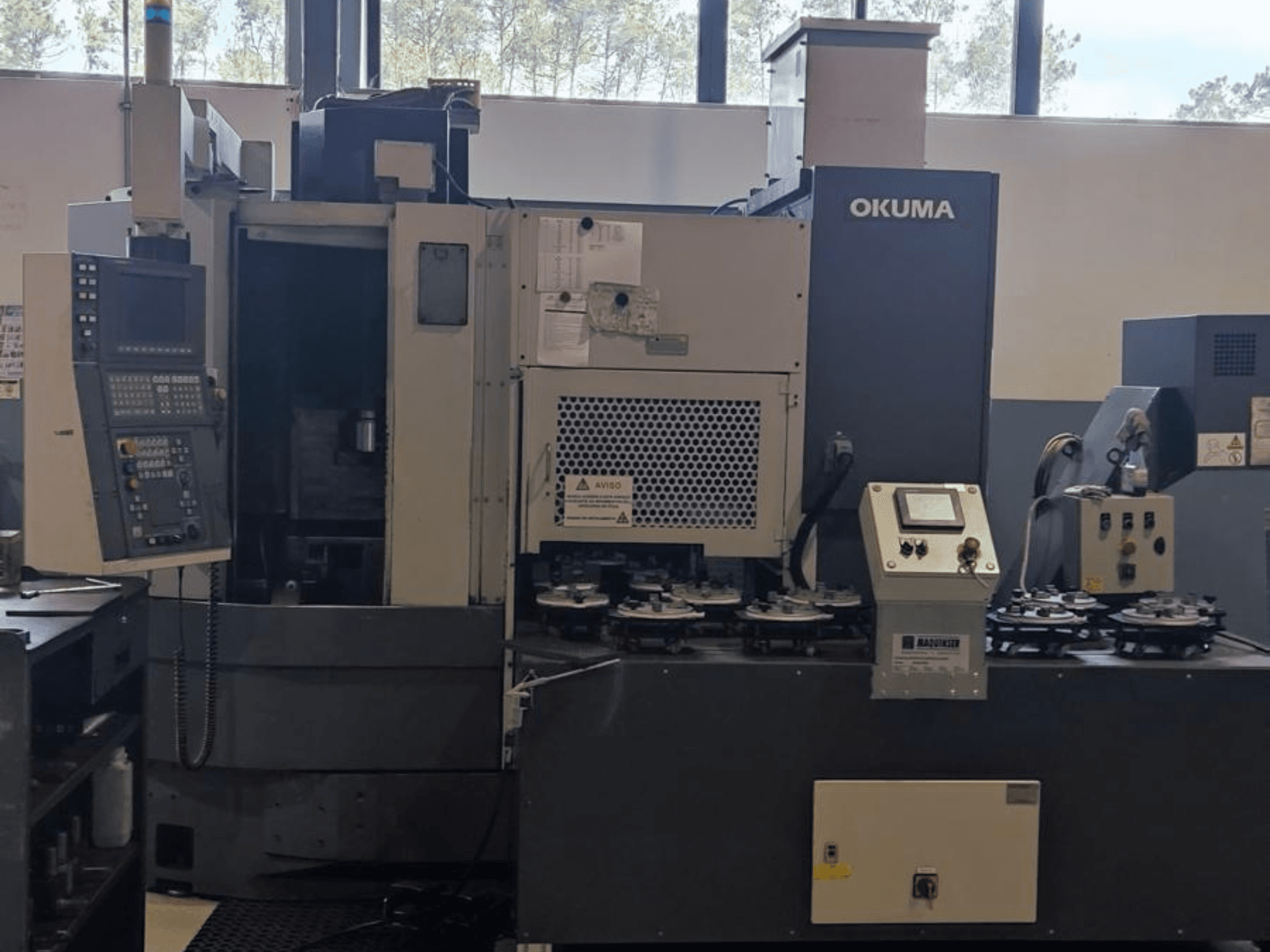Vertikalios tekinimo staklės "Okuma LVT300" iš priekio: valdymo skydelis, įrankių laikikliai ir apdirbimo zona.