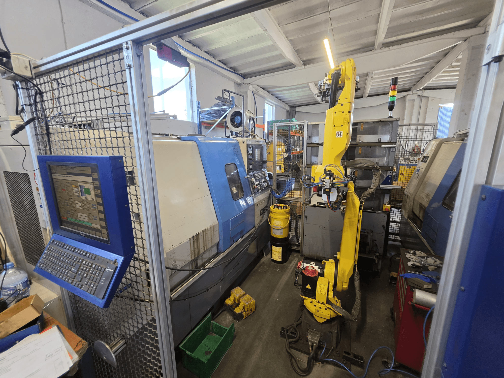 „Hyundai HIT-200C“ horizontalioji tekinimo staklė su „FANUC M-20iA“ robotu; vaizdas iš priekio, kuriame matoma valdymo sąsaja ir staklių konfigūracija.