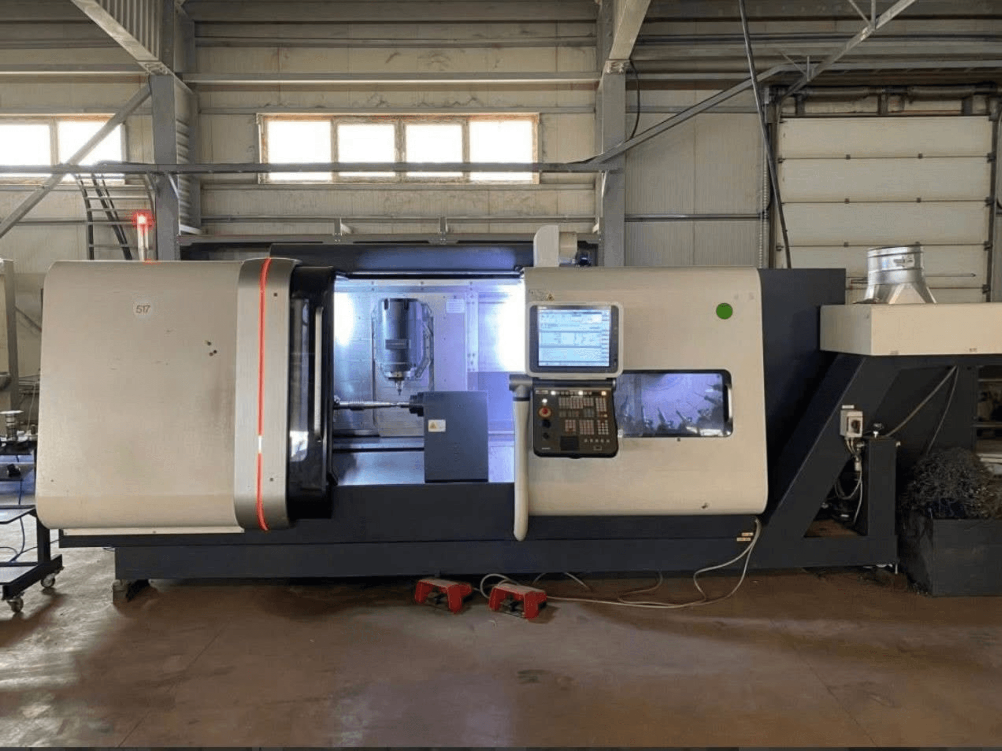 DMG MORI Beta 1250 TC tekinimo frezavimo centras, vaizdas iš priekio su valdymo skydeliu, apšviesta darbo vieta ir matomais pjovimo įrankiais.