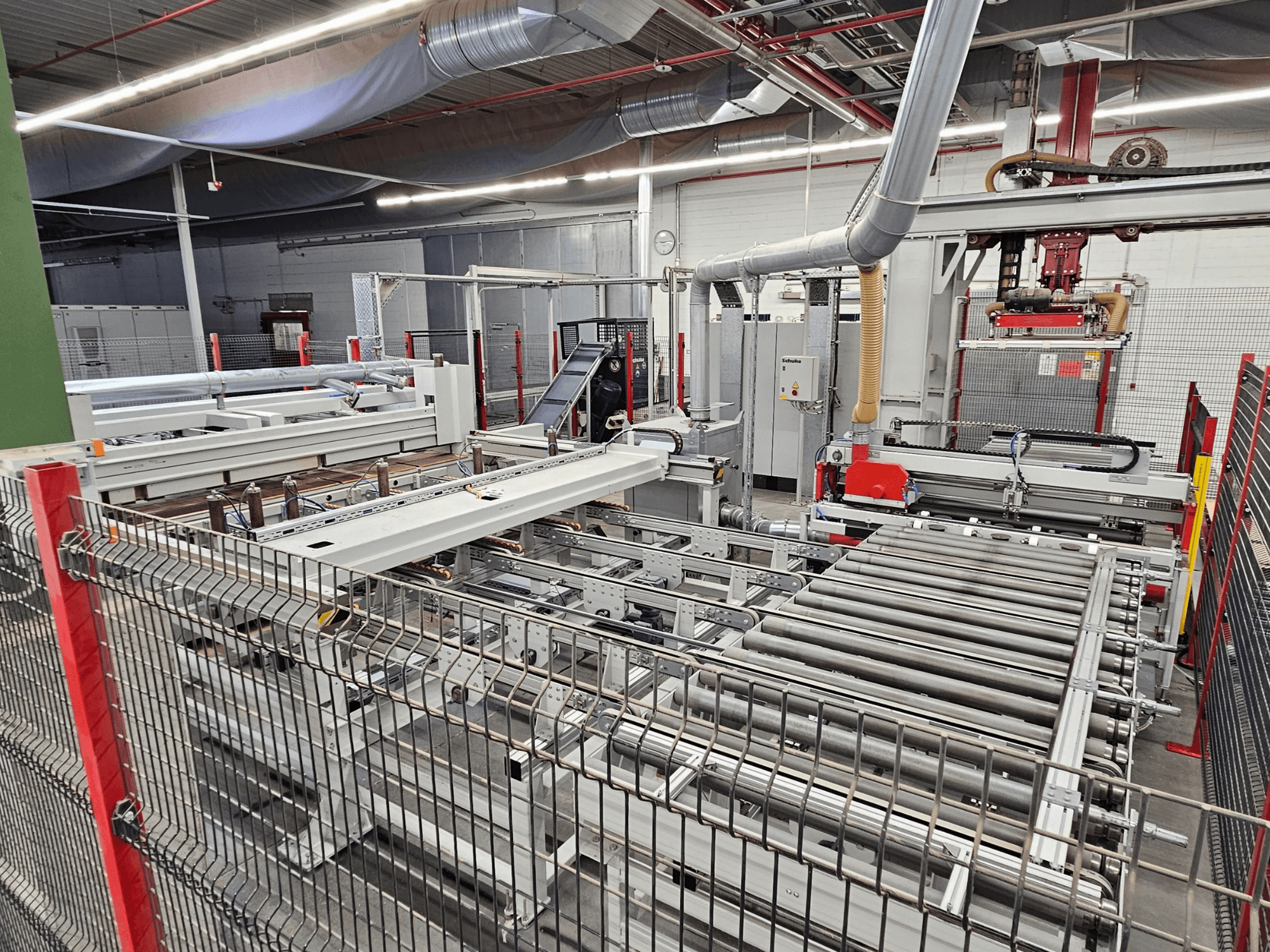 HOLZMA HPP81-3200 skydinis pjūklas, parodytas iš priekio, su konvejerio ritinėliais ir mašinų komponentais dirbtuvėse.