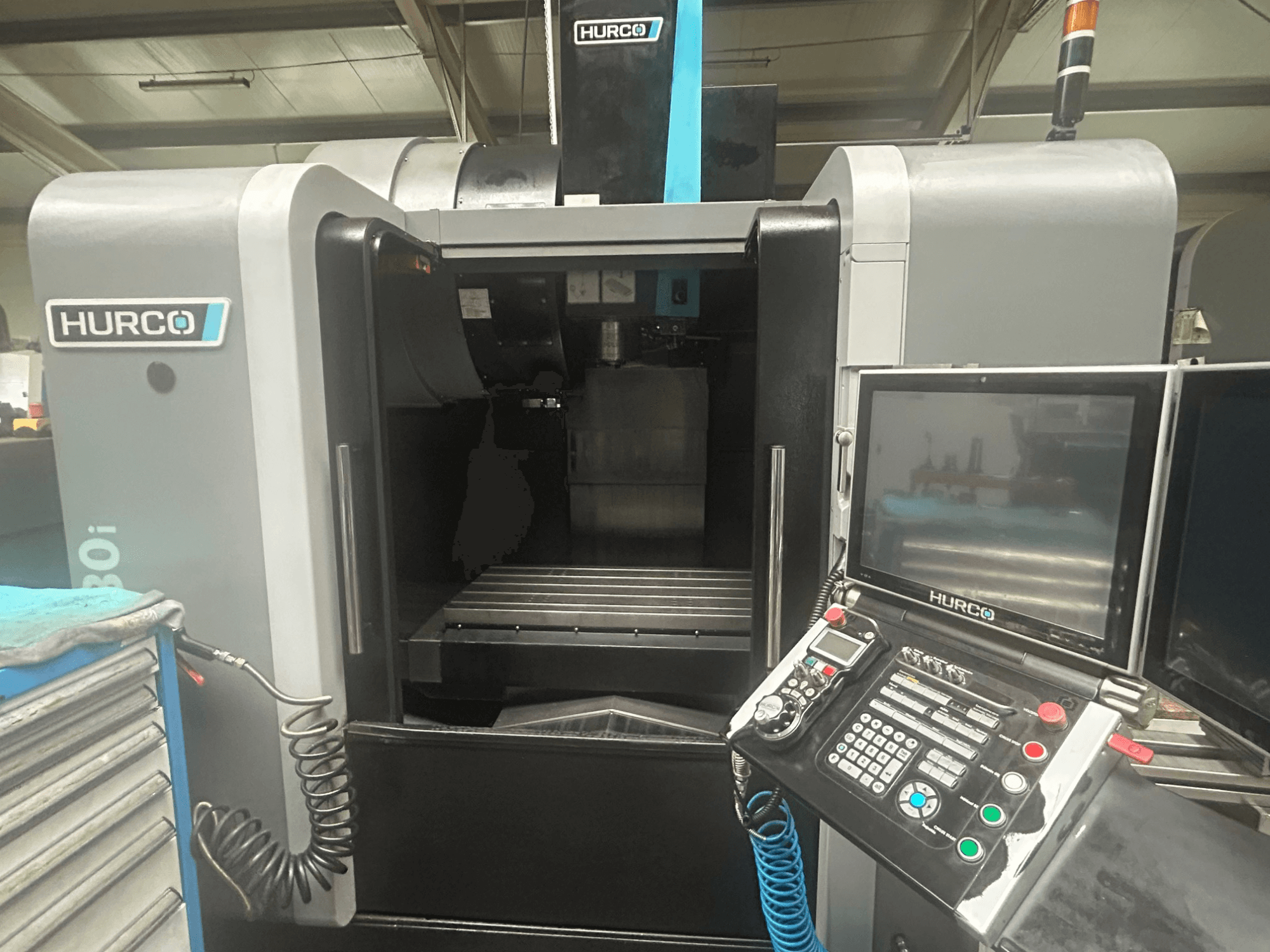 Hurco VM30i CNC staklių priekinis vaizdas, kuriame matomas valdymo skydelis su mygtukais, ekranas ir įrankių laikymo vieta.