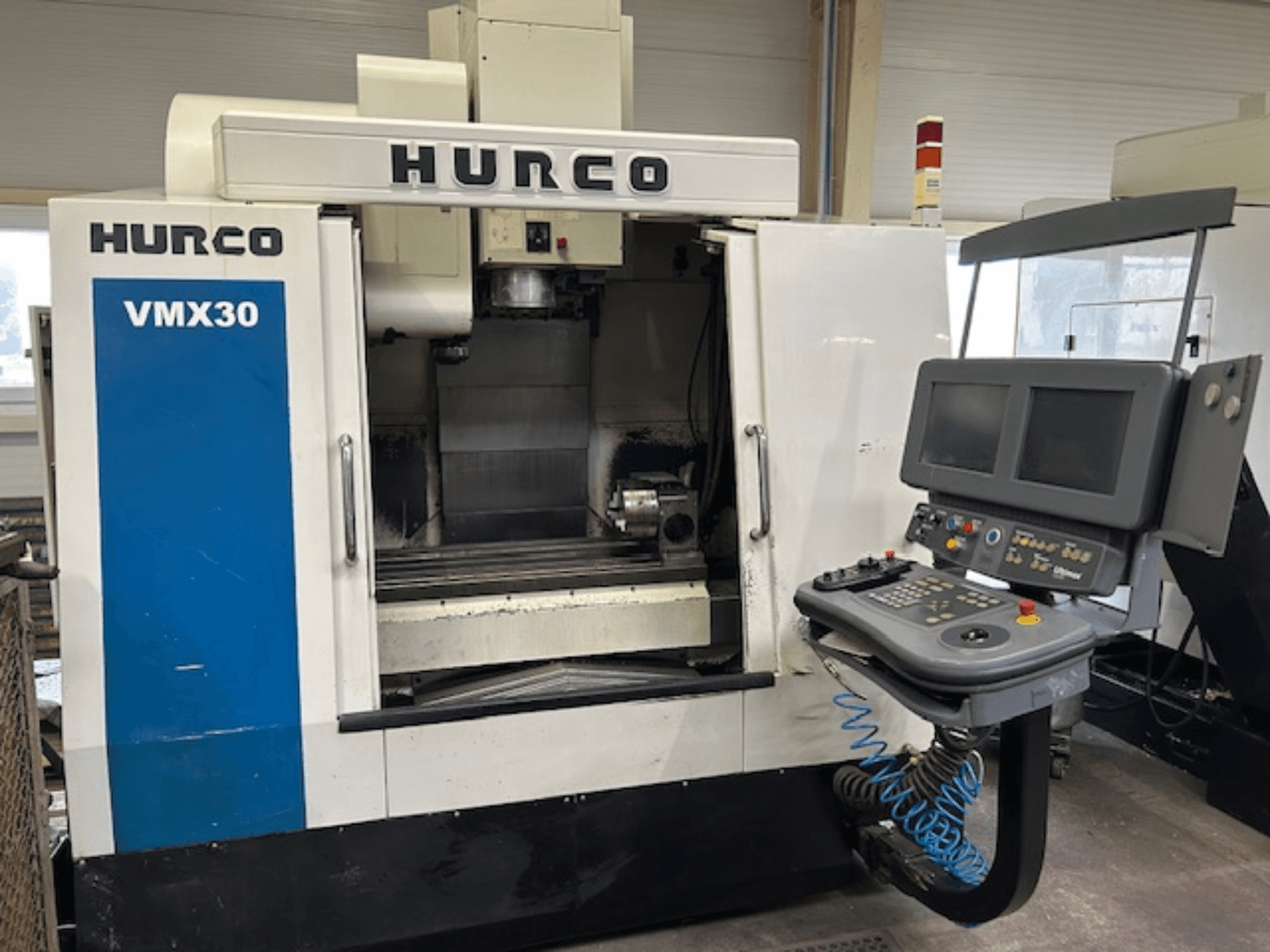 CNC frezavimo staklės "Hurco VMX30" dirbtuvėse, vaizdas iš priekio; valdymo skydelis su dviem ekranais ir valdymo mygtukais.