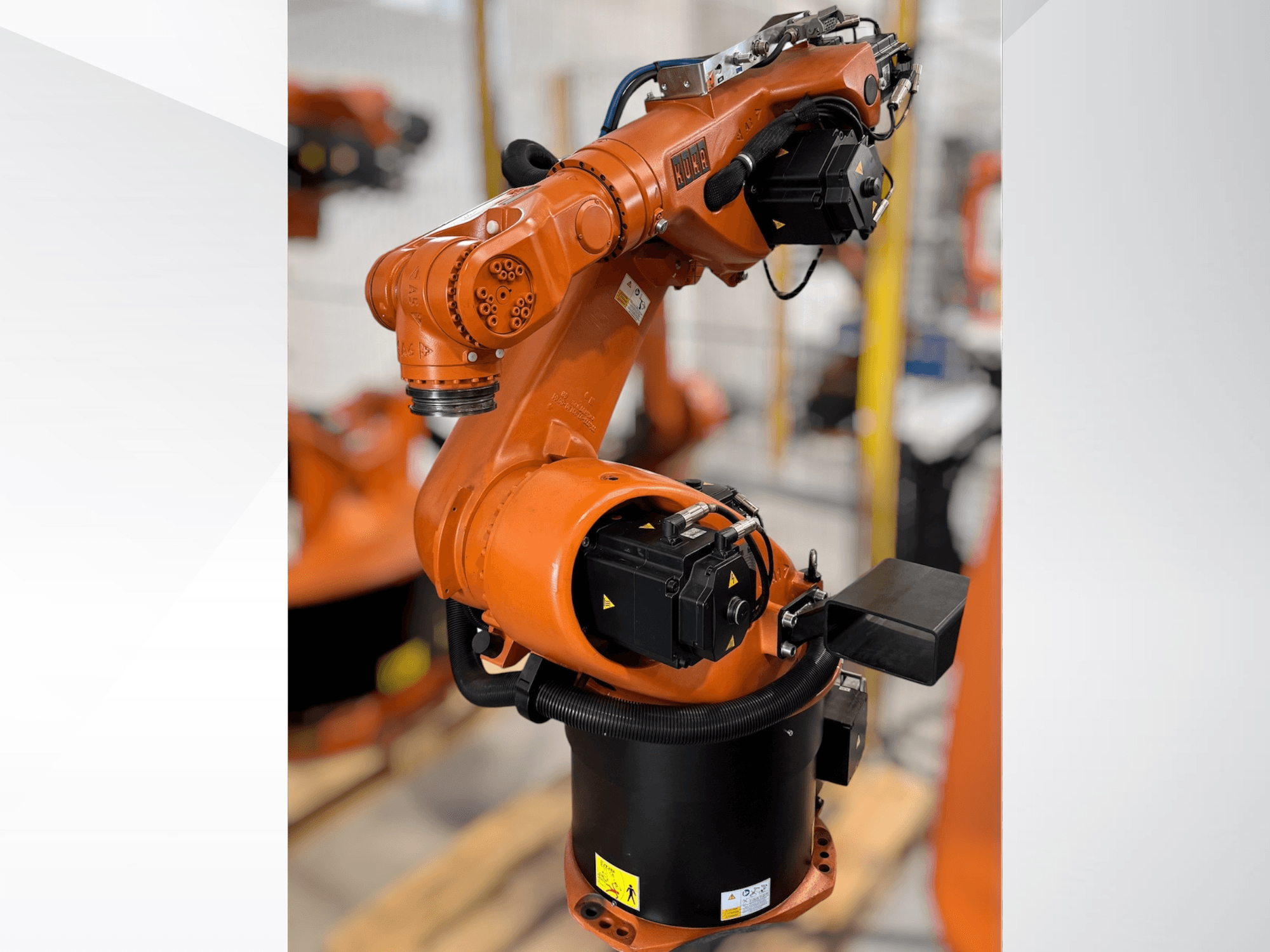 KUKA KR 60-3 roboto ranka oranžinės spalvos; šoninis vaizdas, kuriame matomas pagrindas, sąnariai ir valdymo moduliai, skirti automatizavimo užduotims atlikti.