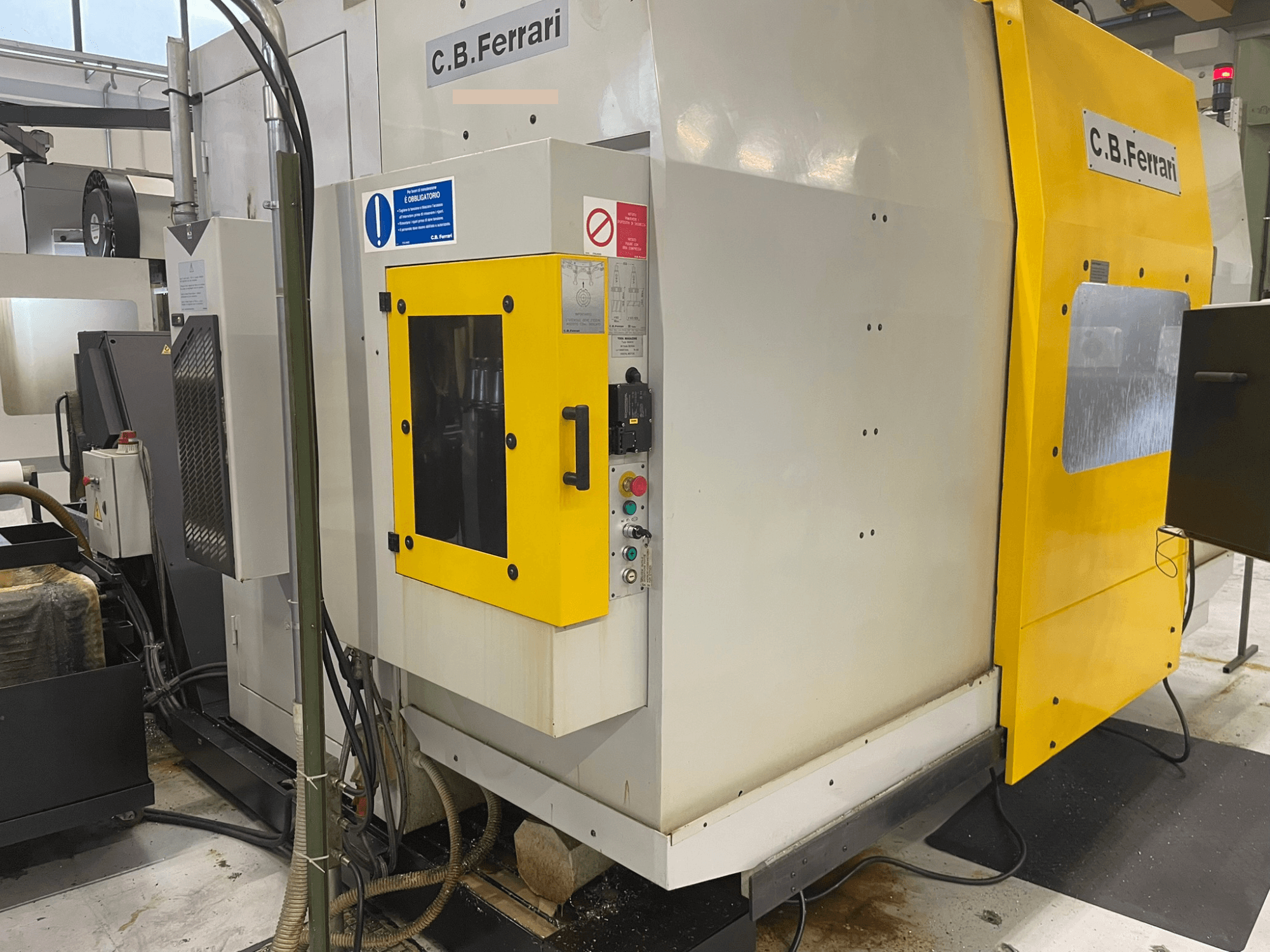 "C.B. Ferrari" pramoninės staklės, vaizdas iš priekio; geltonos durelės, valdymo skydelis ir matomi apdirbimo komponentai.