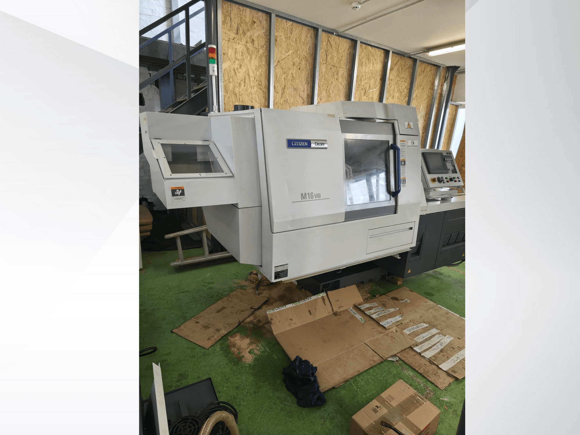 Citizen M16VIII CNC tekinimo staklės iš priekio, su valdymo skydeliu ir saugos įspėjamaisiais žibintais, pastatytos ant žalios grindų dangos.