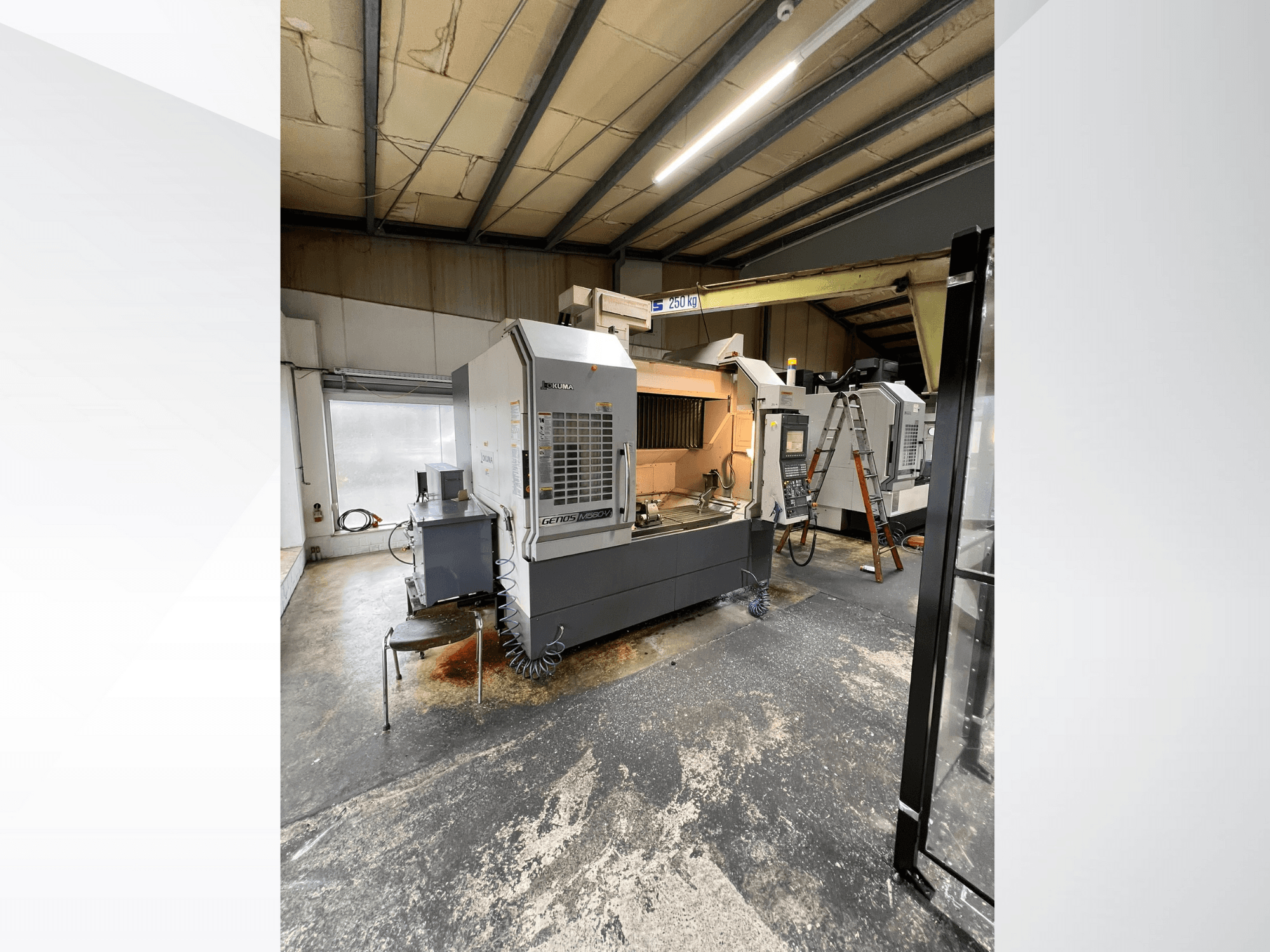 GRETOS 750 CNC staklės dirbtuvėse, vaizdas iš priekio, matomas valdymo skydelis ir darbo zona su įrankiais, fone matomos kopėčios.