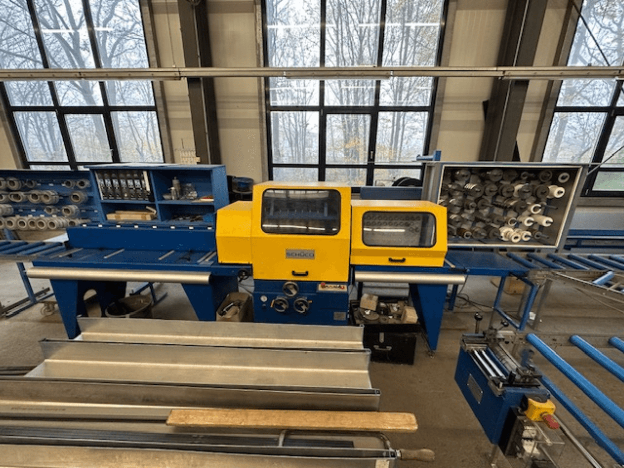 SCHÜCO ISOMAT 4 staklių vaizdas iš priekio: geltonas valdymo skydelis, keli ritiniai ir laikymo skyrius.