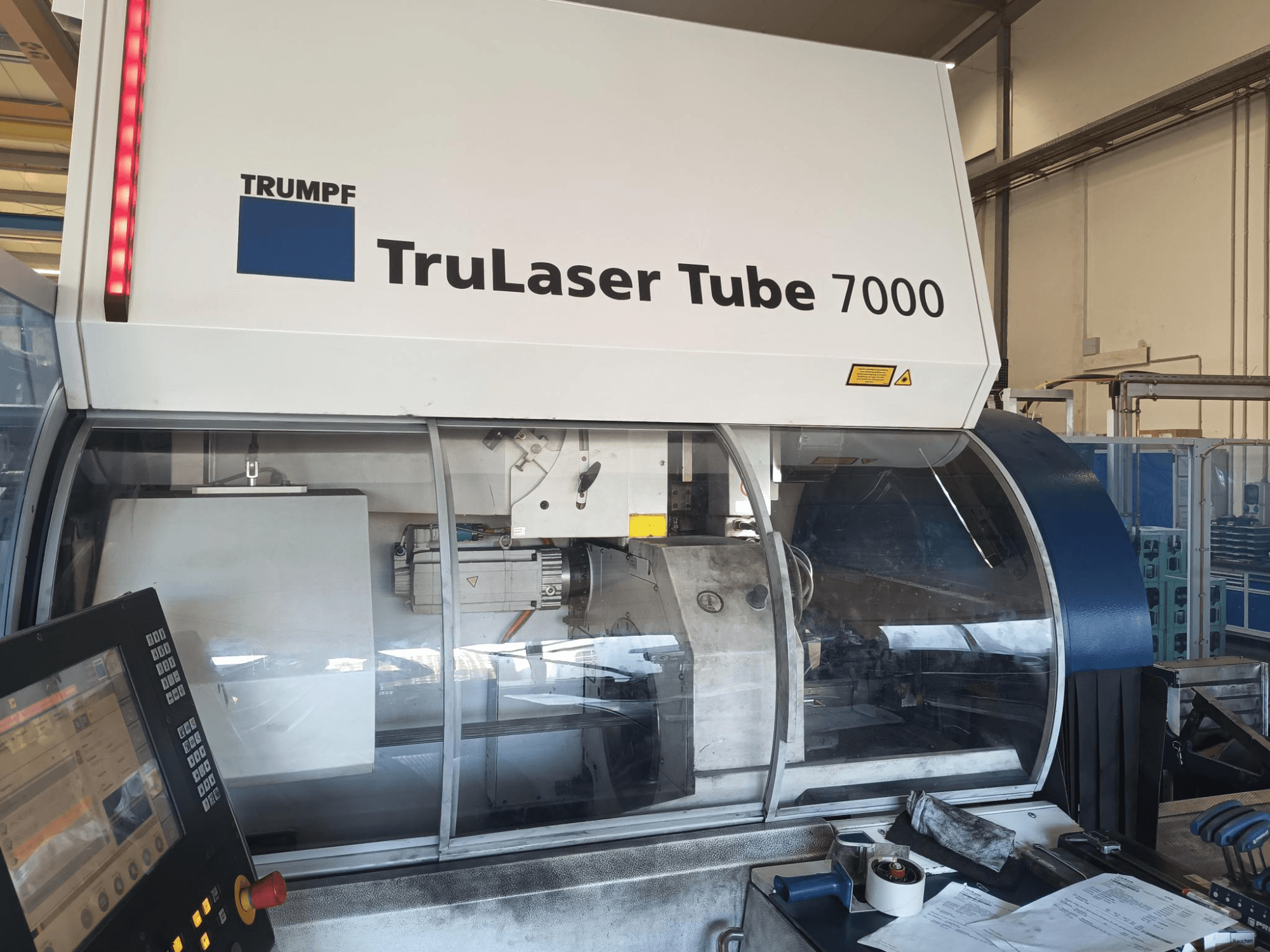 TRUMPF TruLaser Tube 7000, mašinos vaizdas iš priekio su valdymo skydeliu, kuriame matomos lazerinio pjovimo funkcijos ir darbo vieta.
