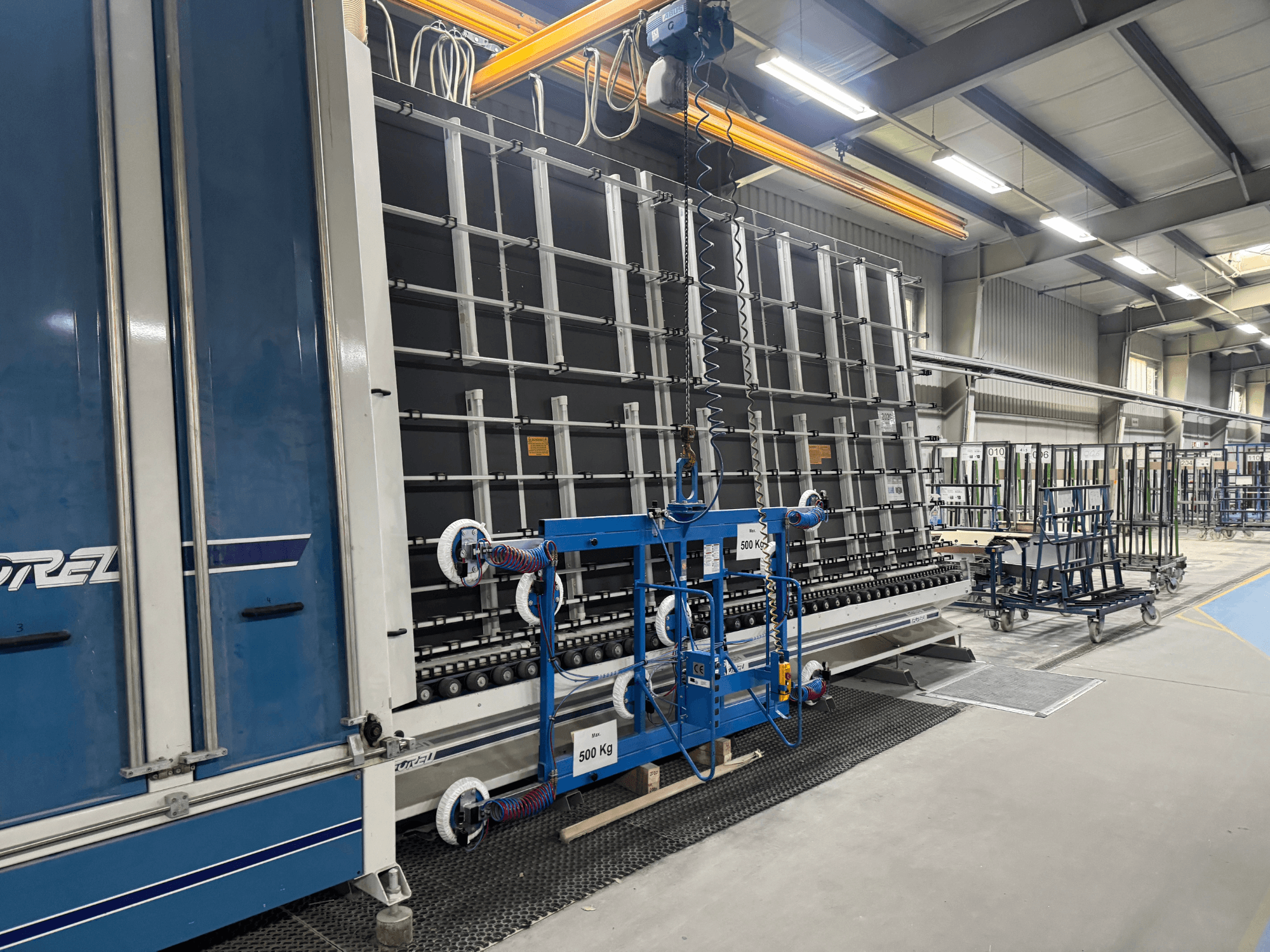 Drel pramoninė įranga su dideliu rėmu ir kėlimo mechanizmu, parodyta iš šono gamykloje.