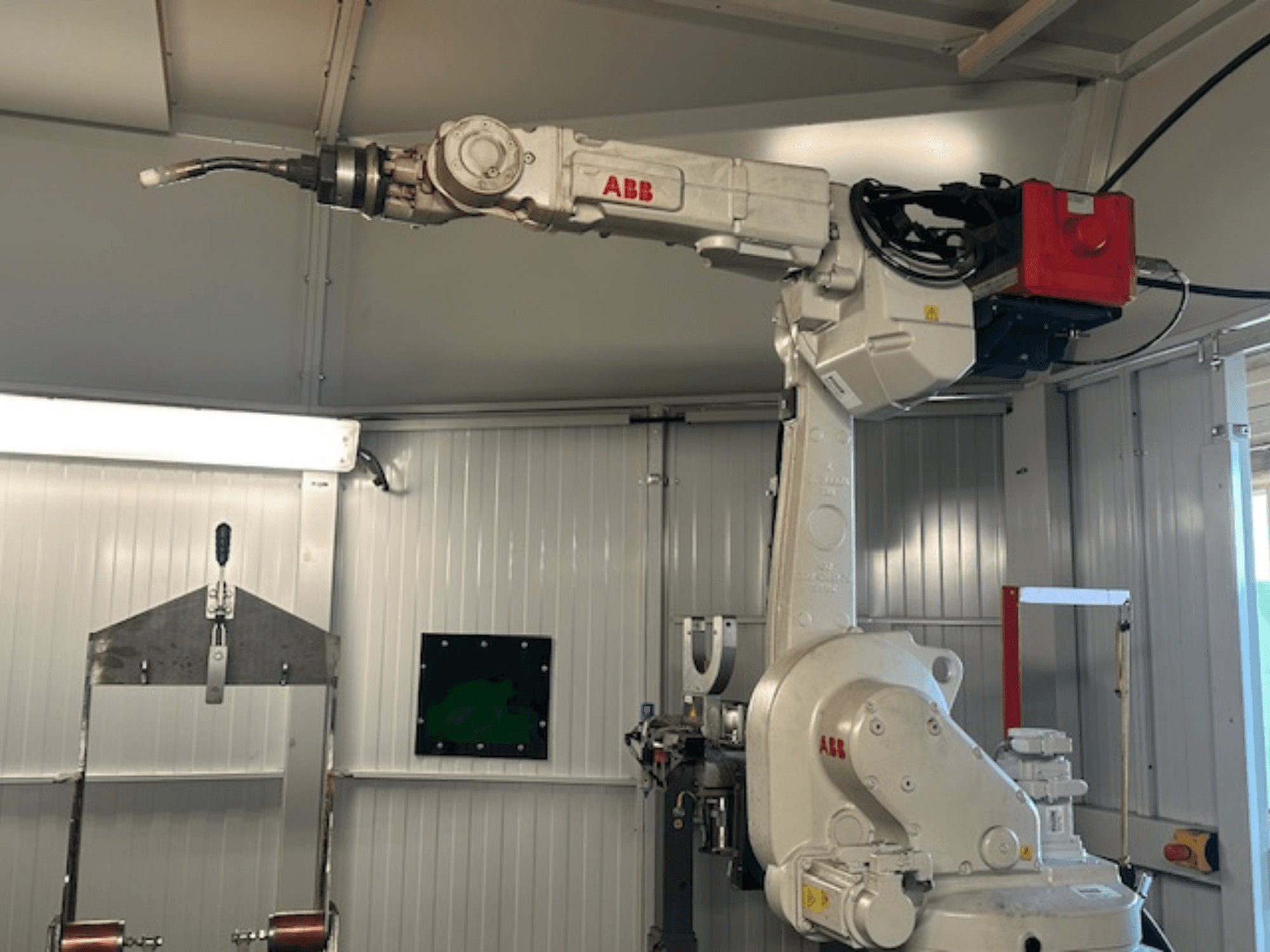 ABB Schweißroboter Flex Arc - šoninis roboto rankos su suvirinimo įrankiu vaizdas, kuriame matomos tokios detalės kaip valdymo skydelis ir kabeliai.