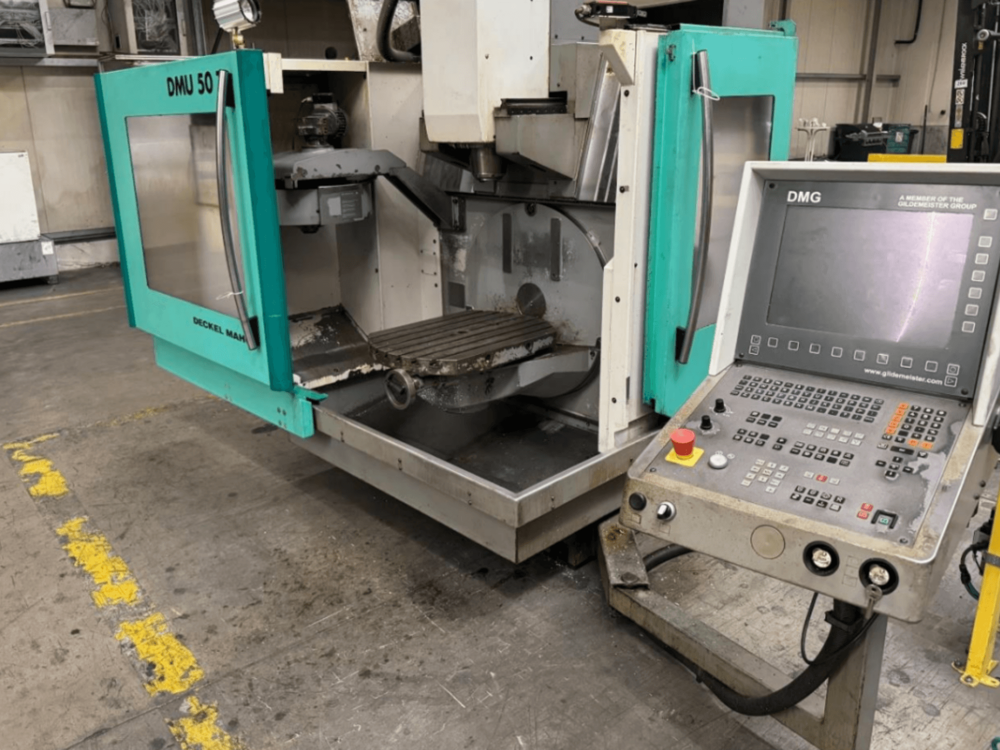 DMG DMU 50 frezavimo staklės su atidarytomis durelėmis, kuriose matomas vidus ir valdymo skydelis, žiūrint iš priekio.