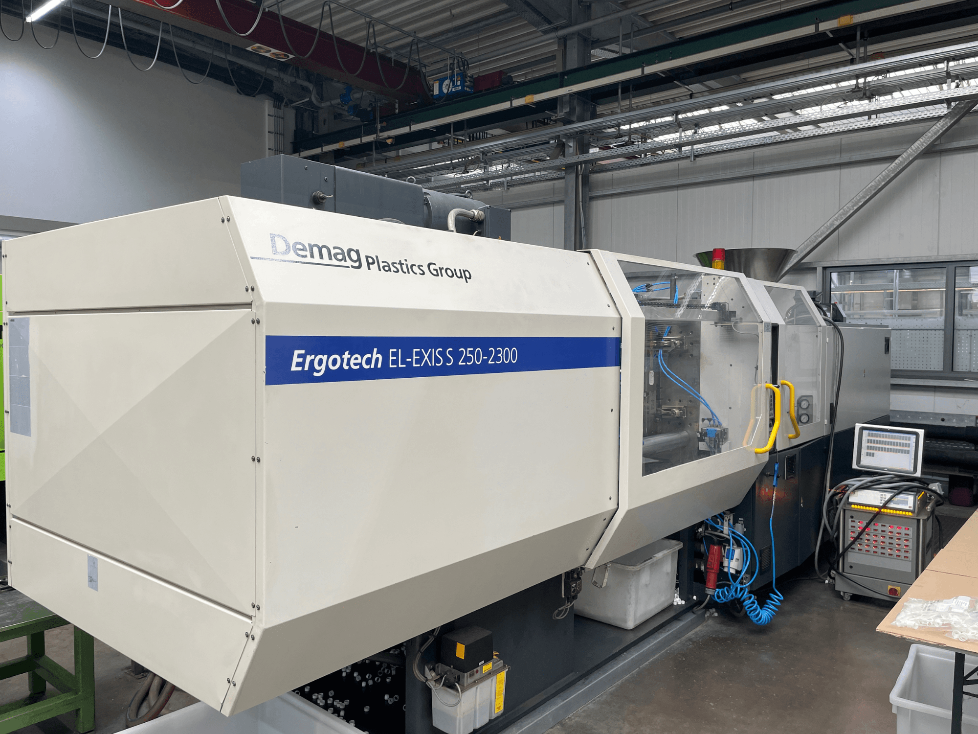 "Demag Ergotech EL-EXIS S 250-2300" šoninis vaizdas, kuriame matomas valdymo skydelis ir padavimo sistema.