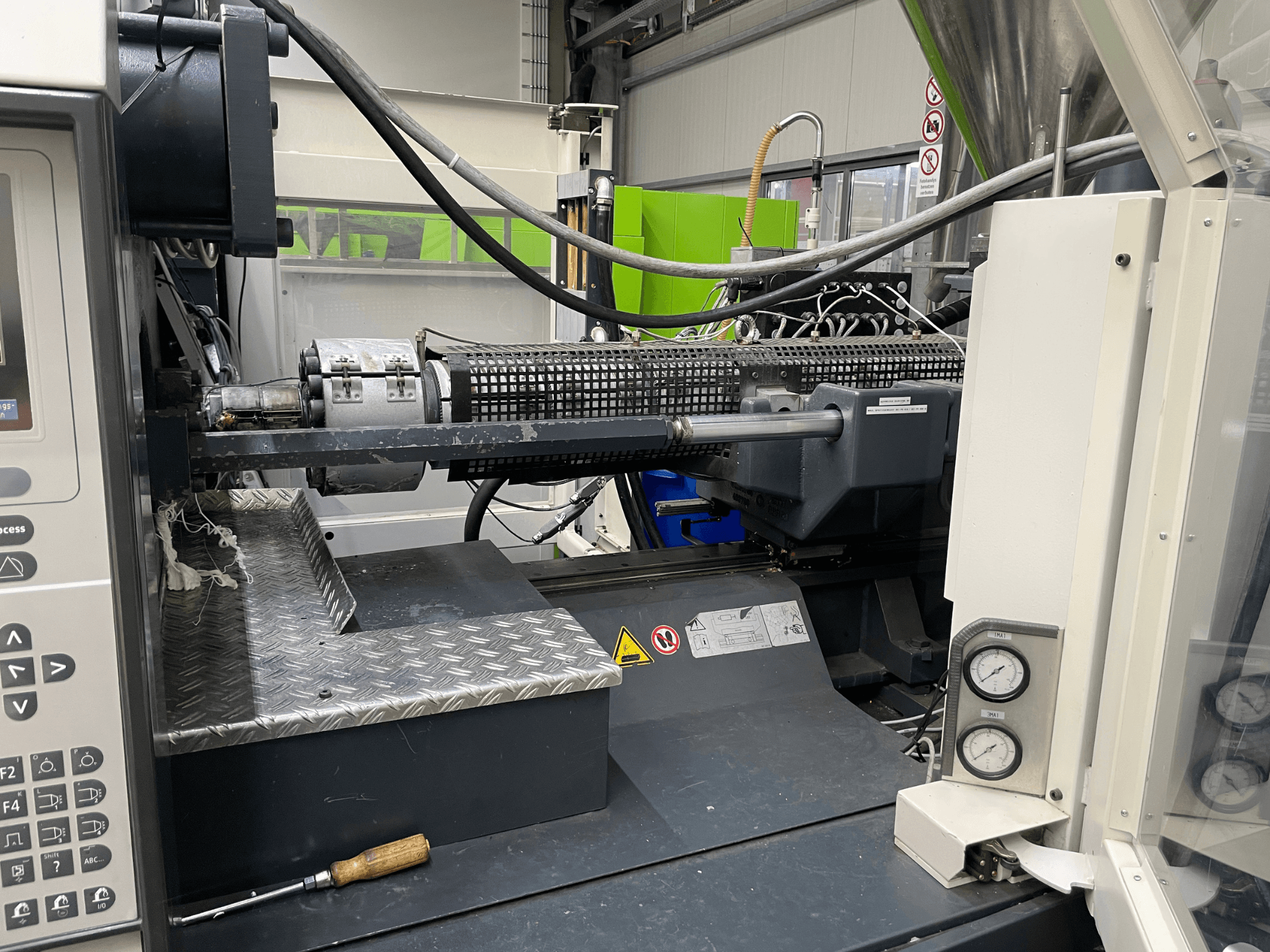 Šoninis liejimo mašinos vaizdas su matomu valdymo skydeliu, ekstruderiu ir slėgio matuokliais, idealiai tinkantis gamybos užduotims.