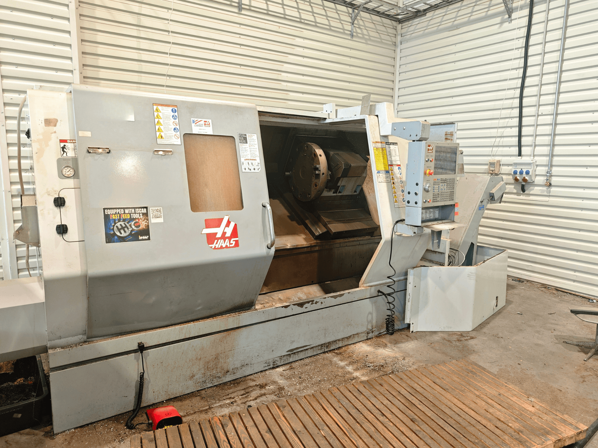 Haas SL-40HE horizontalus tekinimo staklės, vaizdas iš priekio, kuriame matomas valdymo skydas, darbo zona ir saugos etiketės.