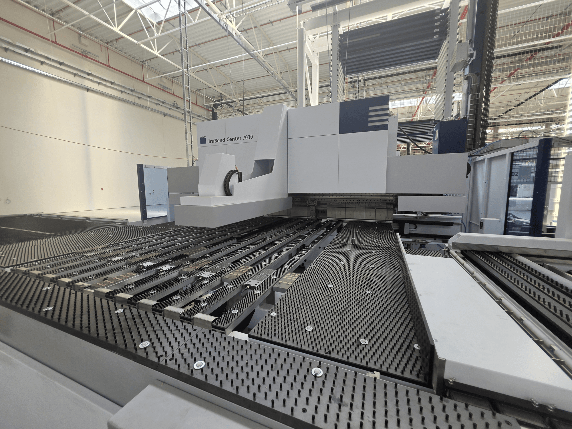 „TRUMPF TruBend Center 7030“ lenkimo staklės gamykloje, vaizdas iš priekio, kuriame matomas sudėtingos konstrukcijos darbo stalas ir lenkimo svirtis.