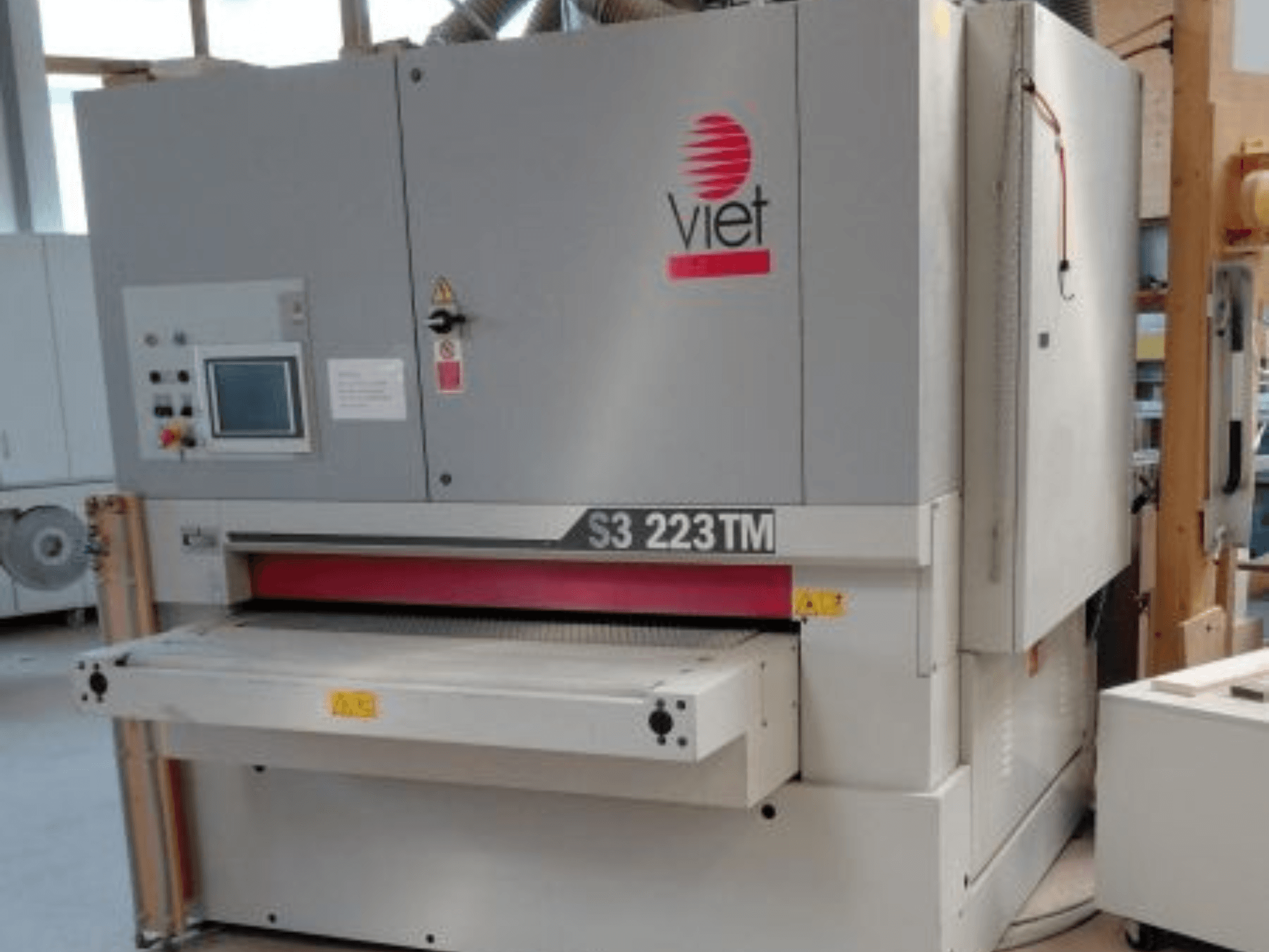 VIET S3 223TM juostinis šlifuoklis, vaizdas iš priekio, kuriame matomas valdymo skydelis, šlifavimo stalas ir saugos etiketės.