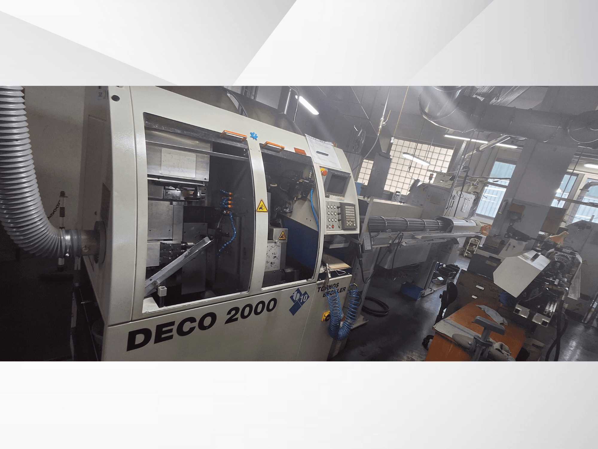 DECO 2000 CNC staklės dirbtuvėse, vaizdas iš priekio, matomi valdikliai ir ilgo ruošinio sąranka dešinėje.