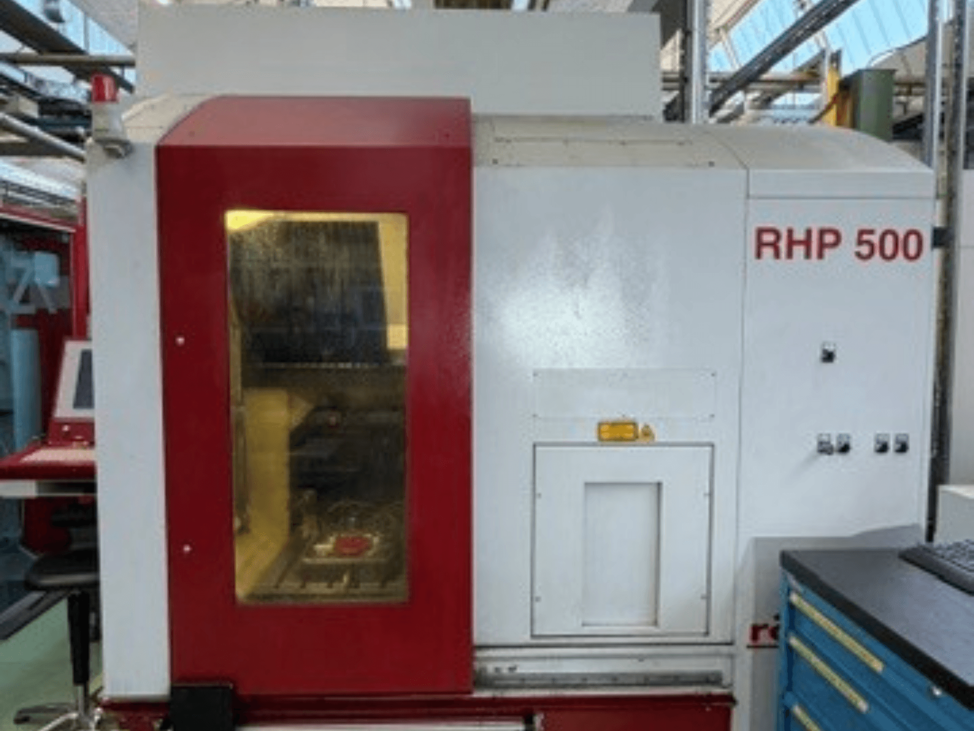 Vertikalusis apdirbimo centras „Röders TEC RHP 500“, vaizdas iš priekio, kuriame matomas valdymo pultas ir permatomas langelis, pro kurį matosi vidus.