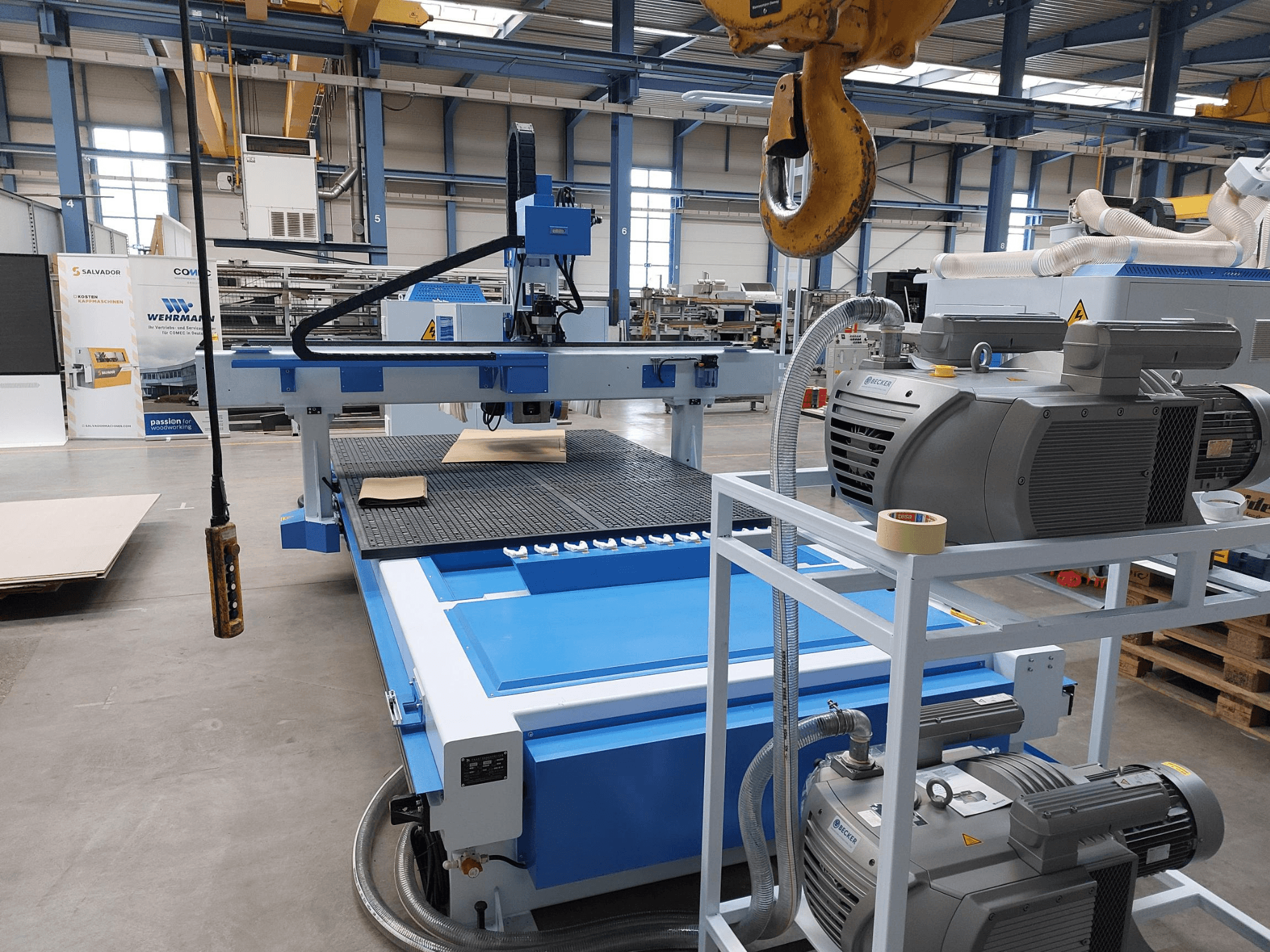 CNC medžio apdirbimo centras „QUICK CNC UA 481“, vaizdas iš priekio, kuriame matomas valdymo pultas, varikliai ir darbo paviršius su medžio ruošiniu.