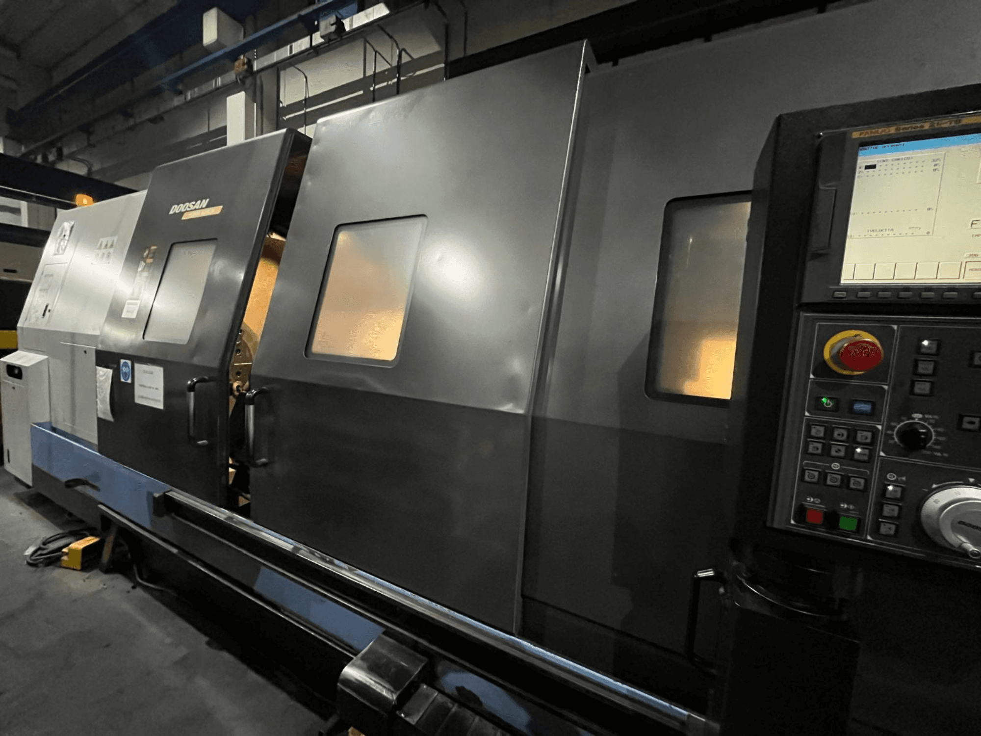 "Doosan" CNC tekinimo staklės iš priekio, su valdymo skydeliu ir operatoriaus sąsaja su matomu skaitmeniniu ekranu ir mygtukais.