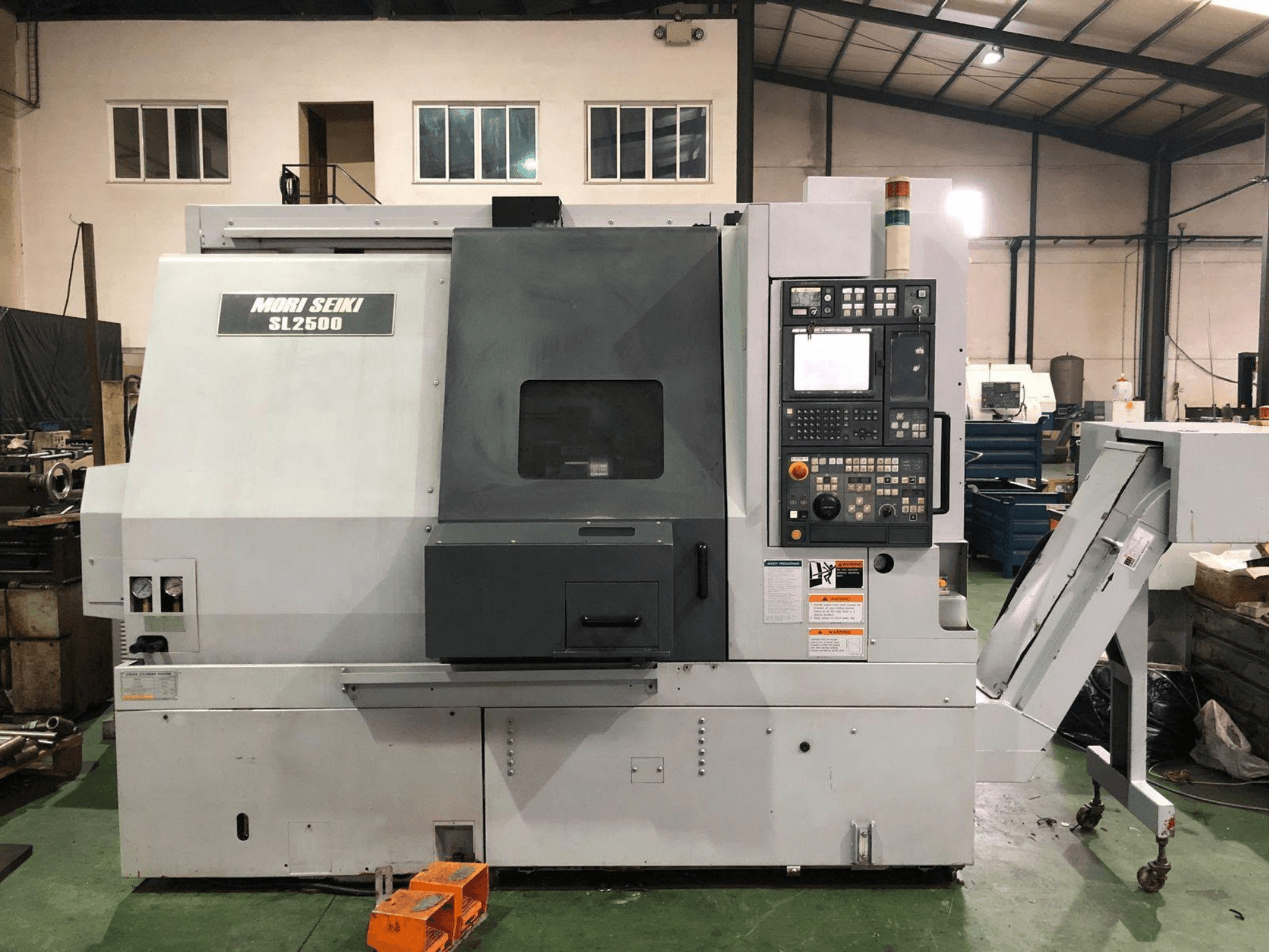DMG Mori Seiki SL 2500 Y tekinimo-frezavimo centras, šoninis vaizdas, kuriame matomas valdymo pultas ir drožlių konvejeris.