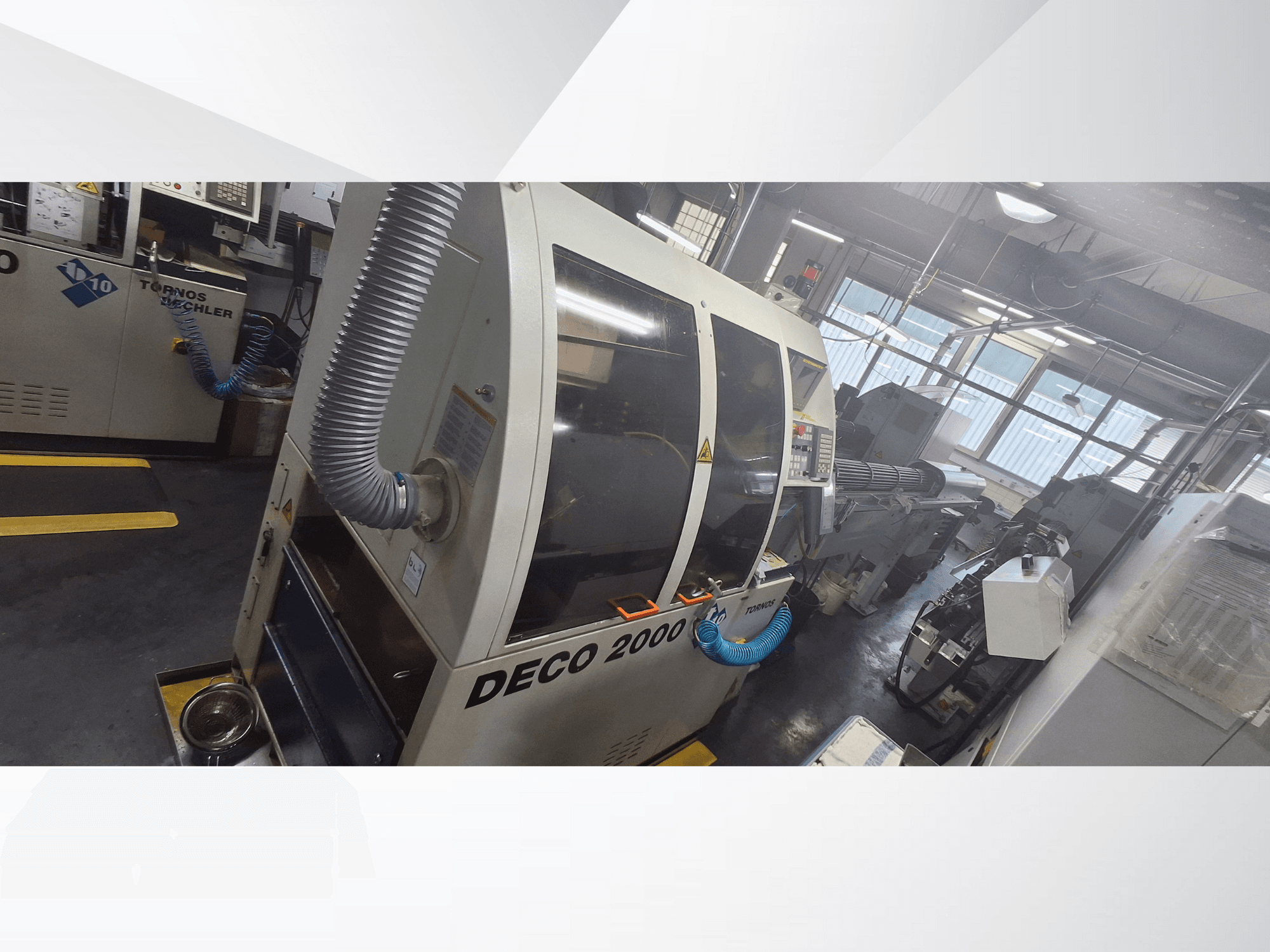 DECO 2000 CNC staklės dirbtuvėse, vaizdas iš priekio, su ventiliacijos žarna ir valdymo skydeliu, skirtos tiksliam apdirbimui.