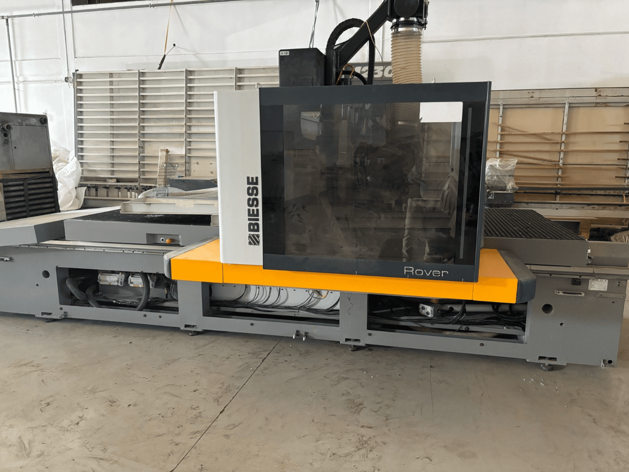 "Biesse Rover" CNC apdirbimo centras, vaizdas iš priekio, su dideliu valdymo skydeliu, geltonais akcentais ir matomais mechaniniais komponentais.