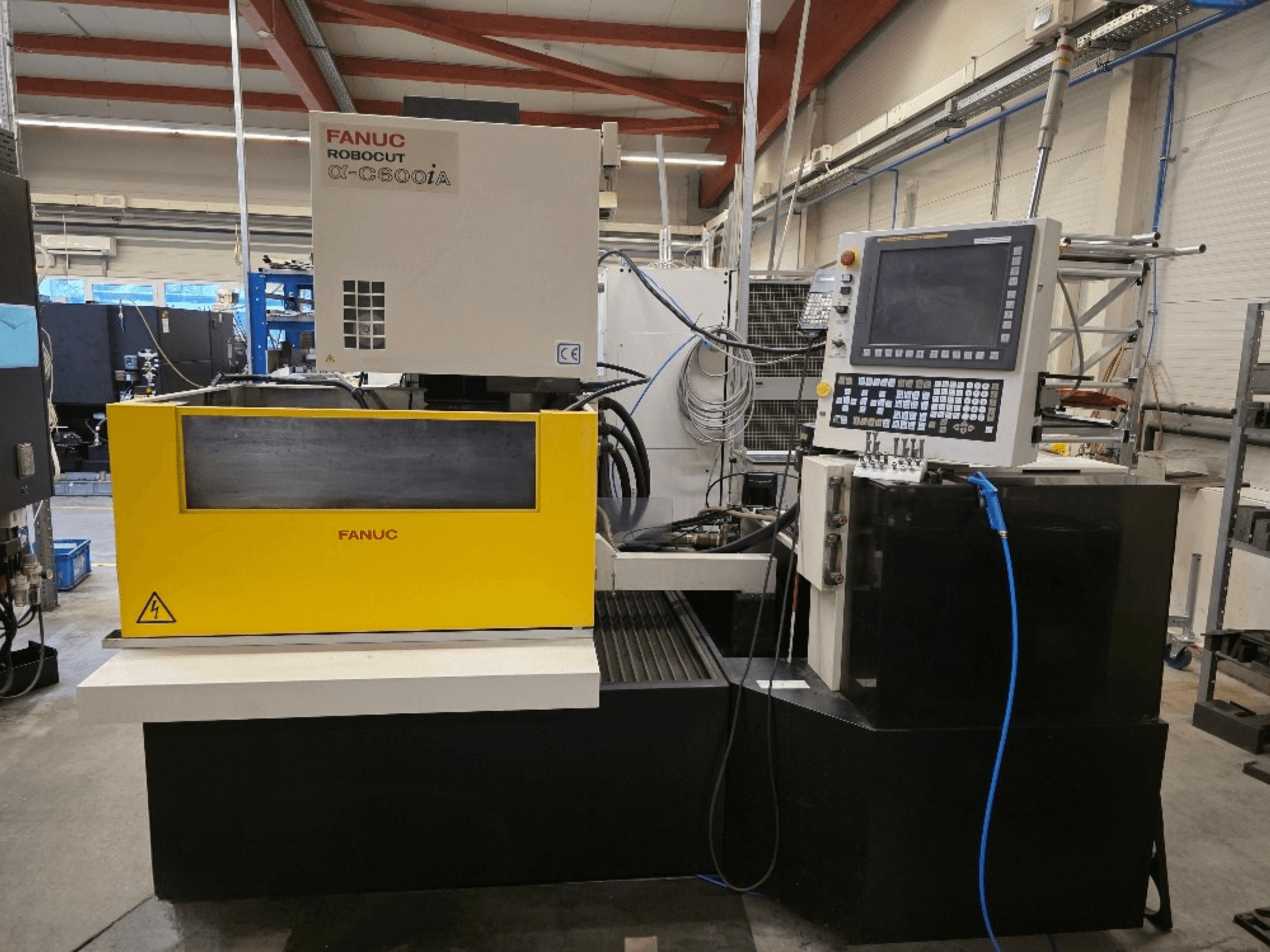 FANUC Robocut α-C600iA vielos pjovimo staklės, vaizdas iš priekio, geltonas valdymo skydelis ir skaitmeninis ekranas.